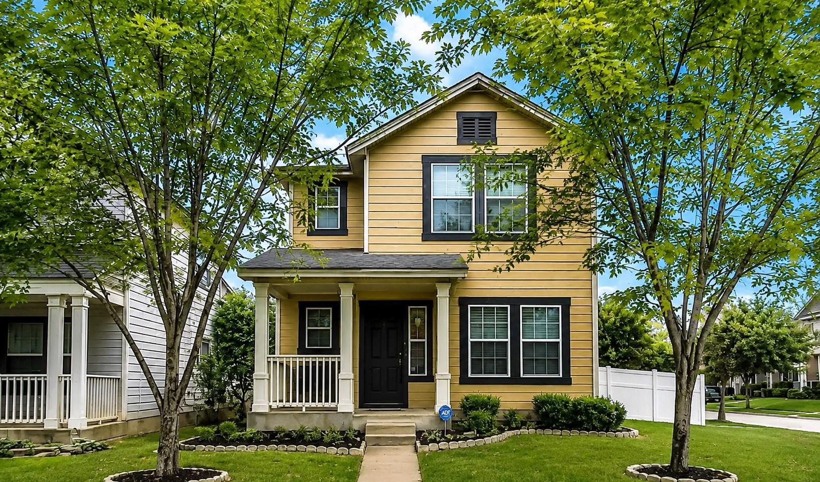 Shade trees frame a two-story residence with a we