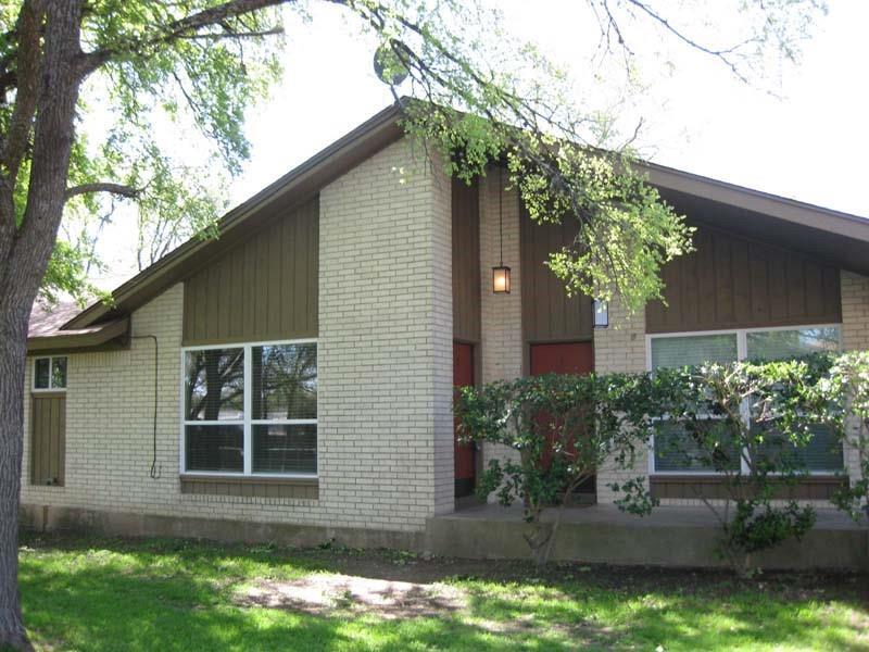 A classic brick exterior, framed by mature trees,