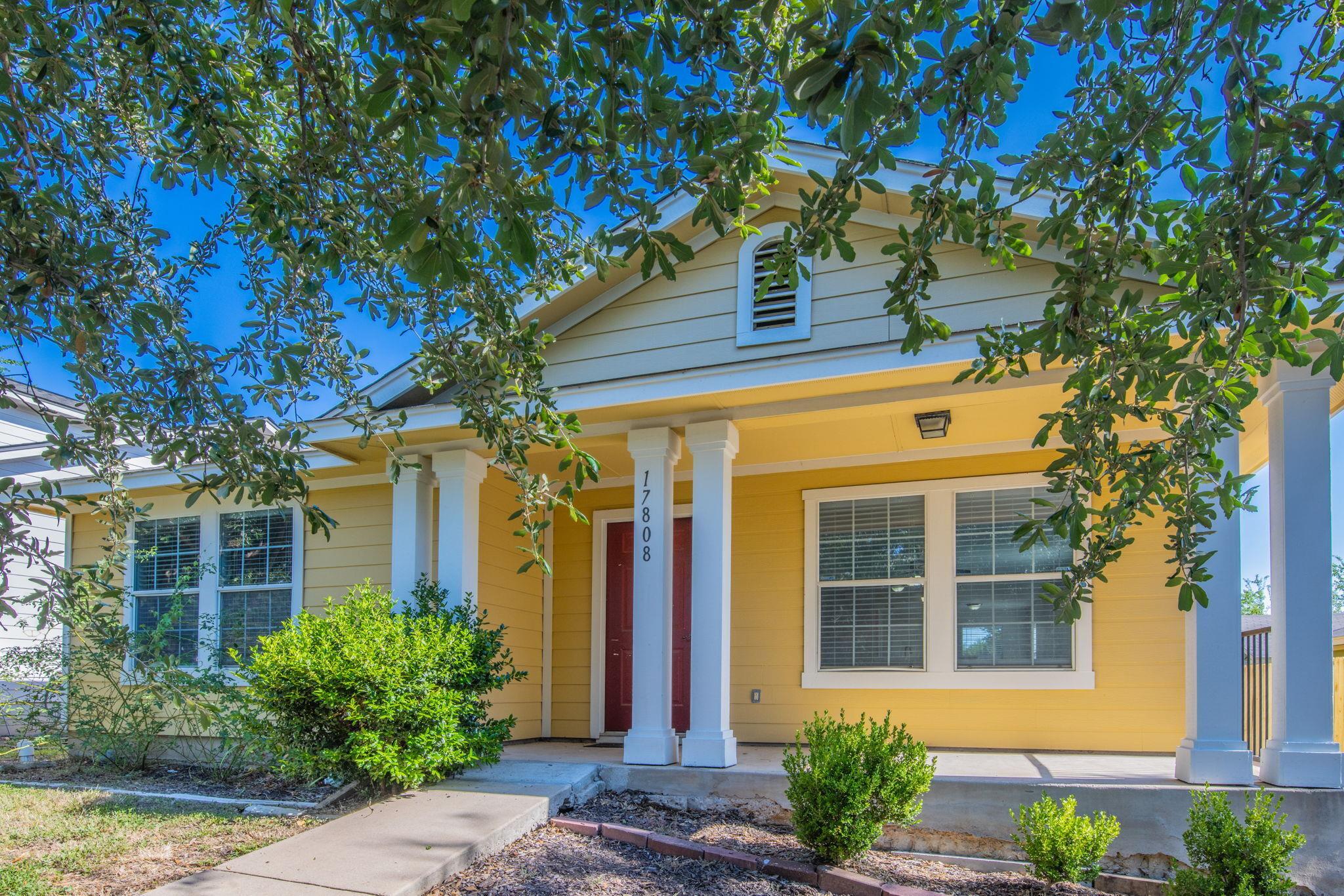 A welcoming yellow facade with a red front door i