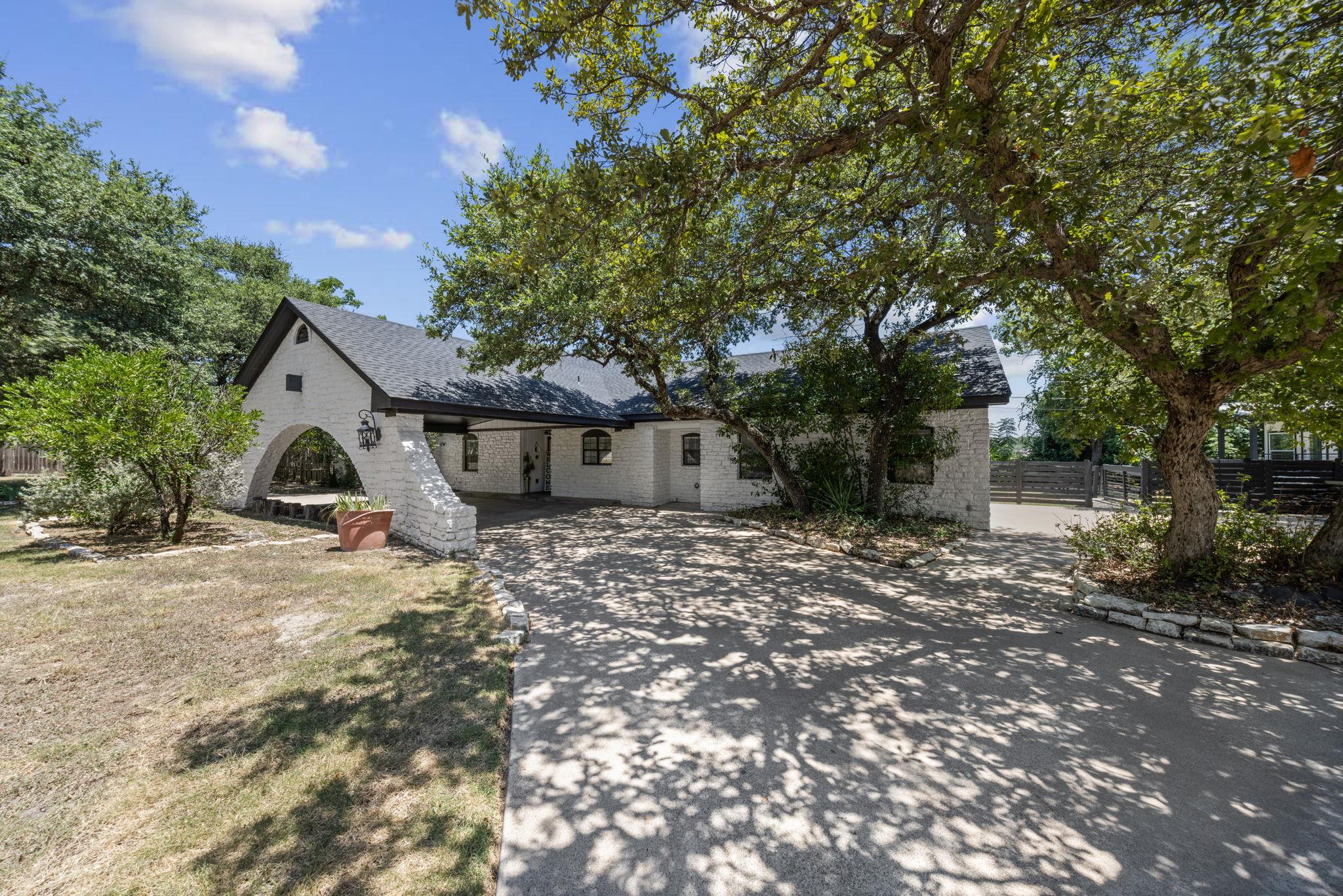 Mature shade trees frame a charming stone exterio