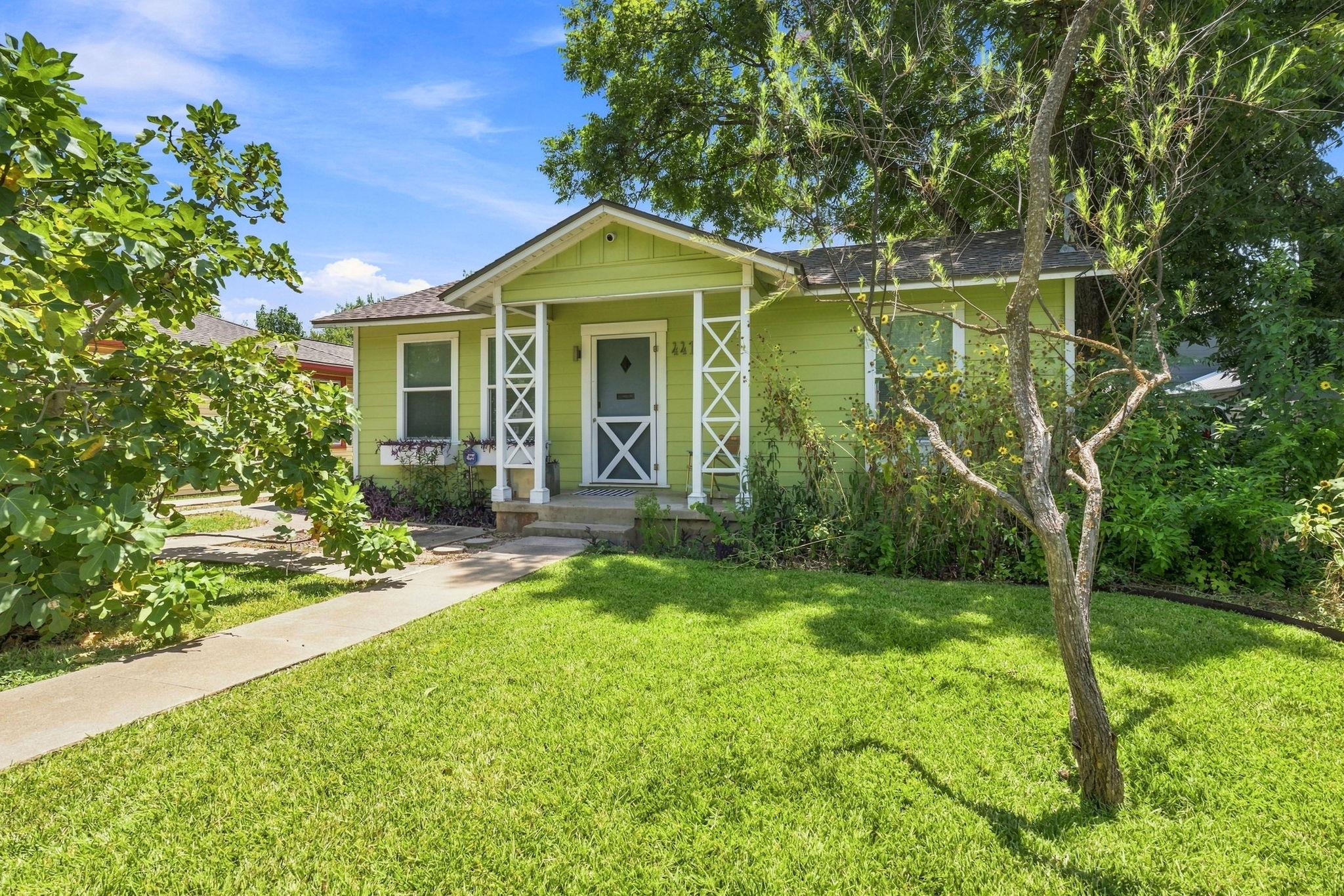 A vibrant green home featuring a welcoming porch,