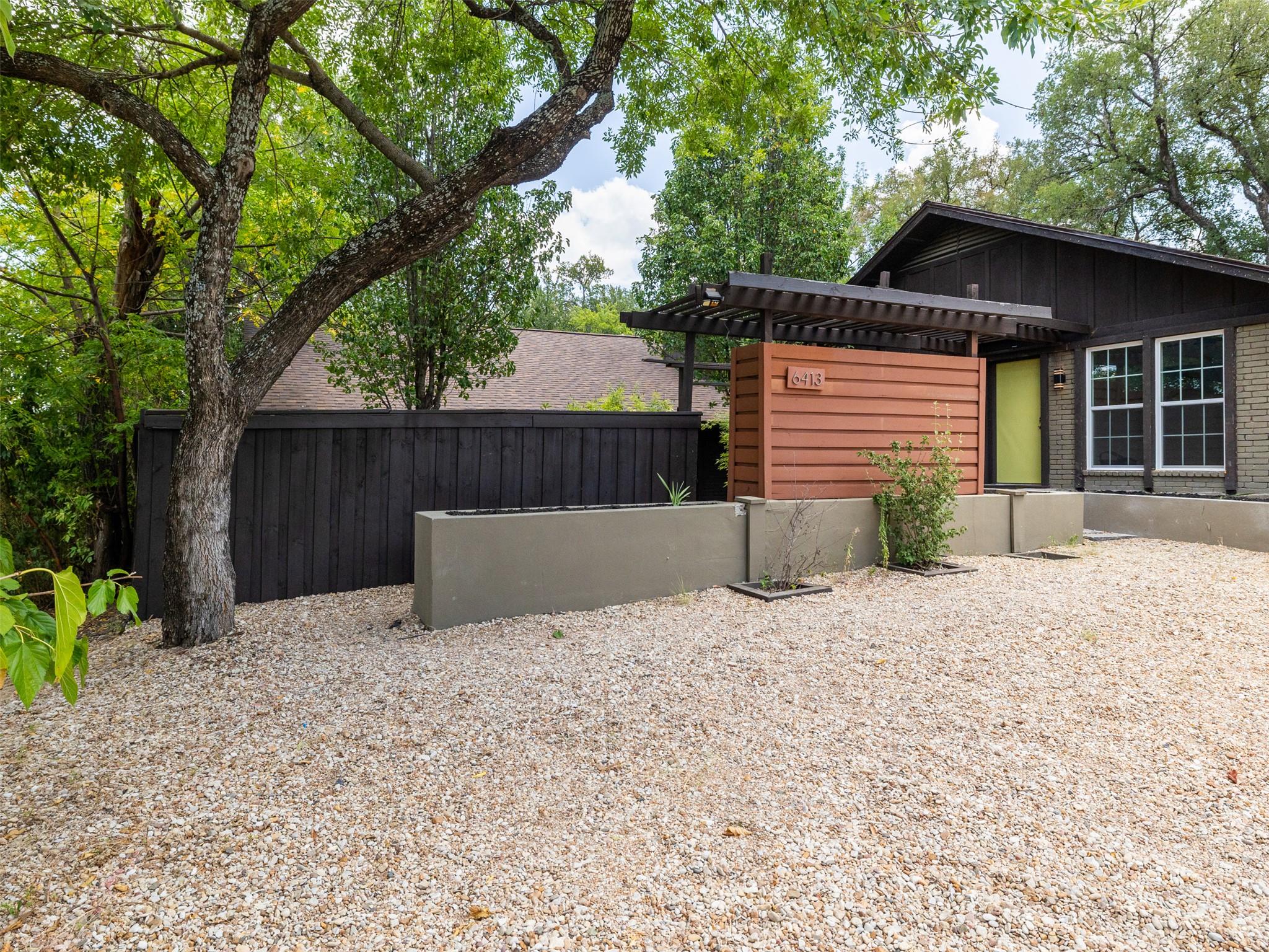 Mature trees shade the gravel yard and contempora