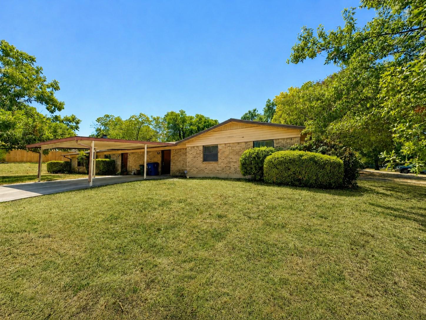 Mature trees frame a brick exterior with an attac