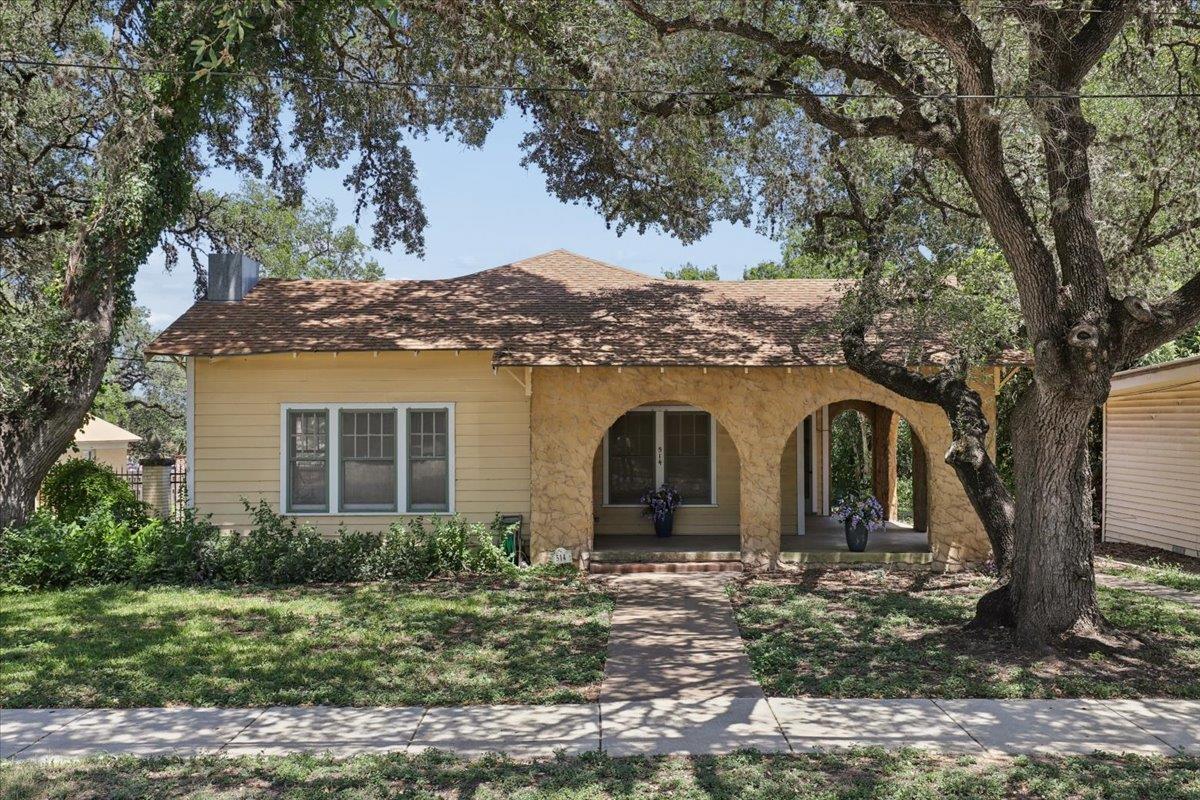 Mature shade trees frame a charming home featurin