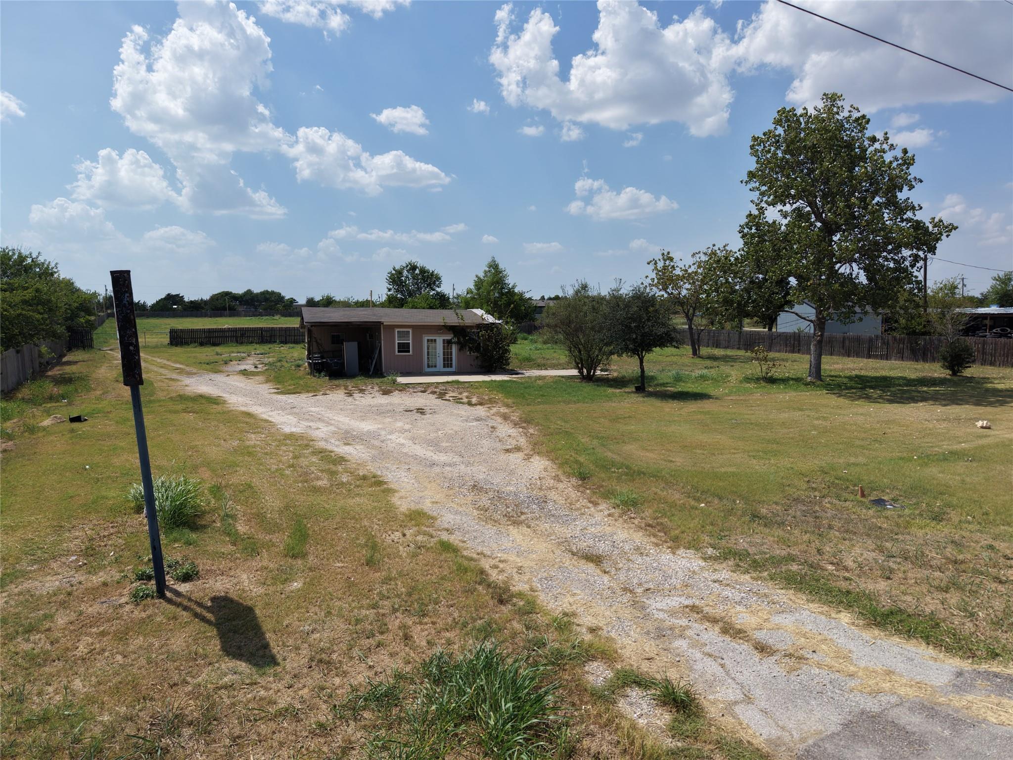 A long, gravel driveway leads to a modest structu
