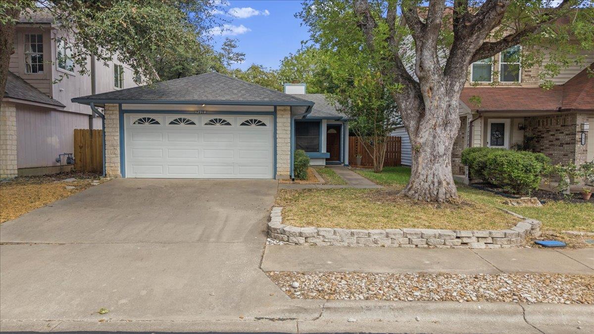 Mature trees shade the concrete driveway leading 