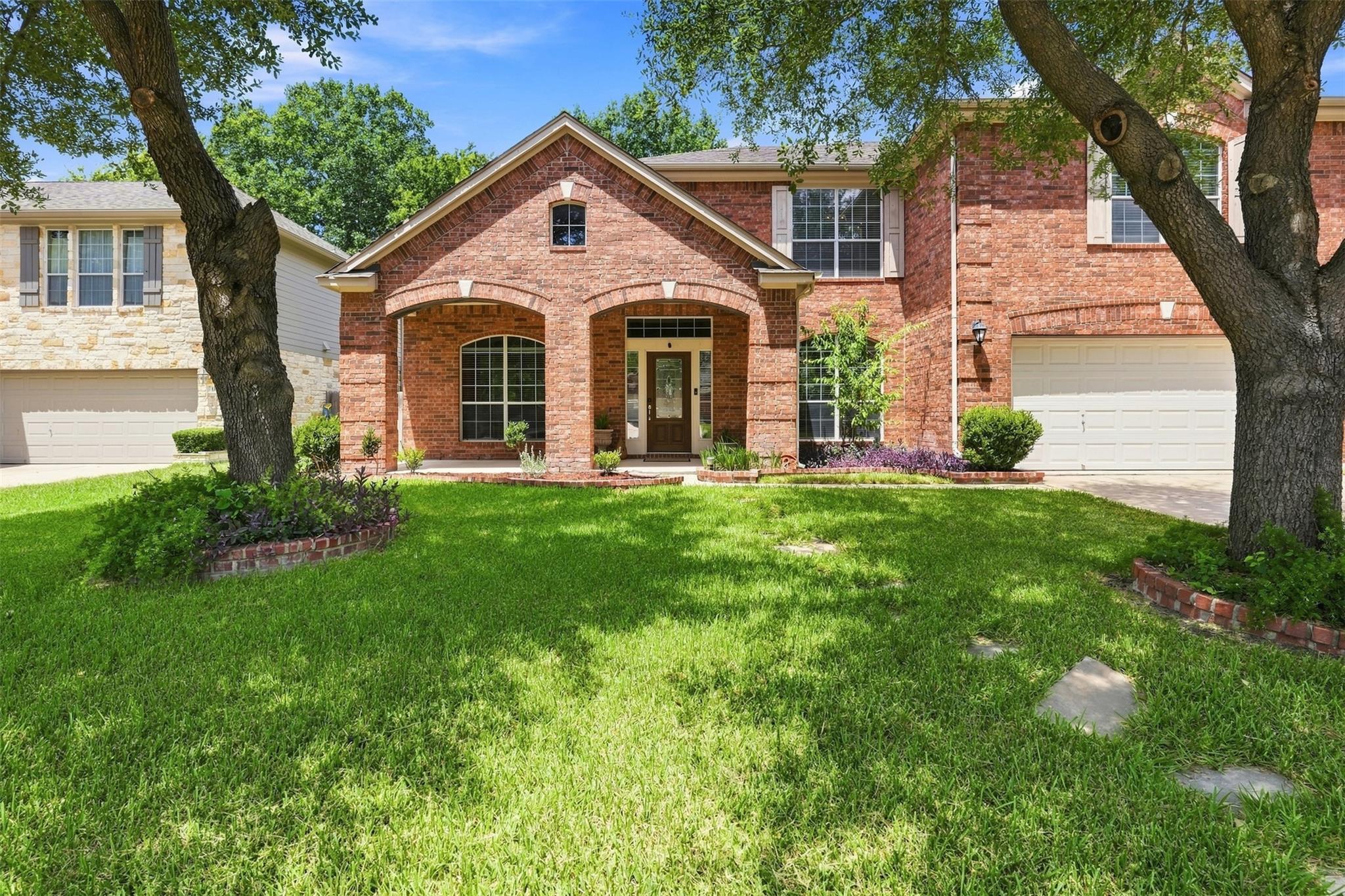 Mature trees shade a classic brick facade with an
