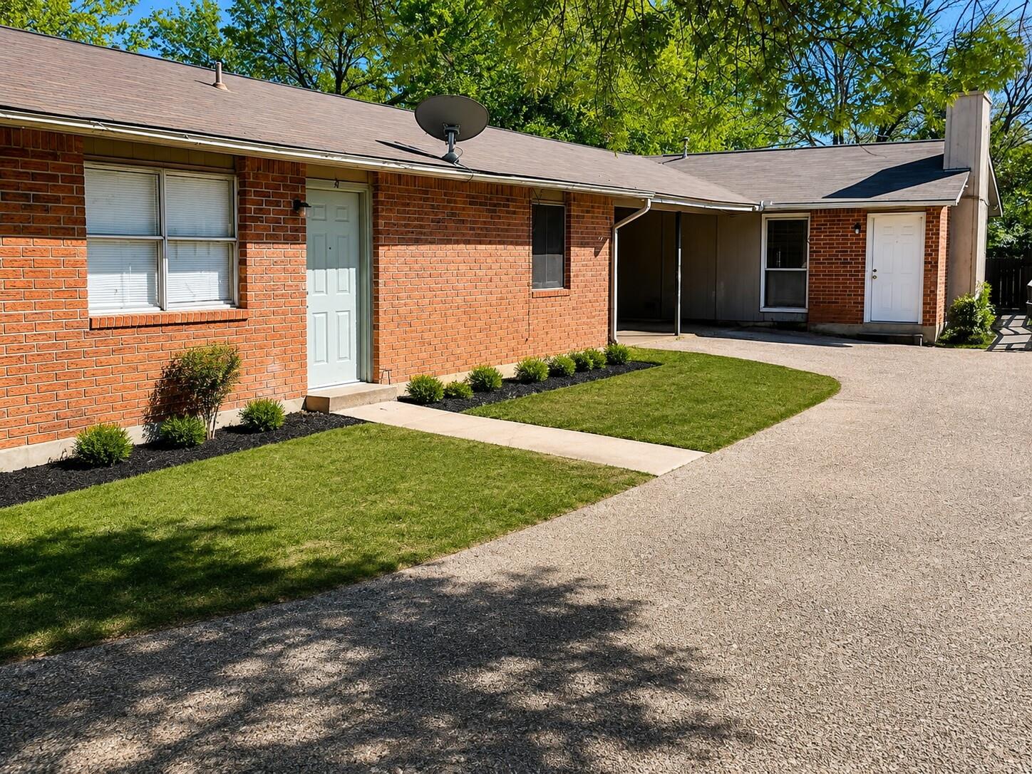 A well-maintained lawn and paved driveway complem