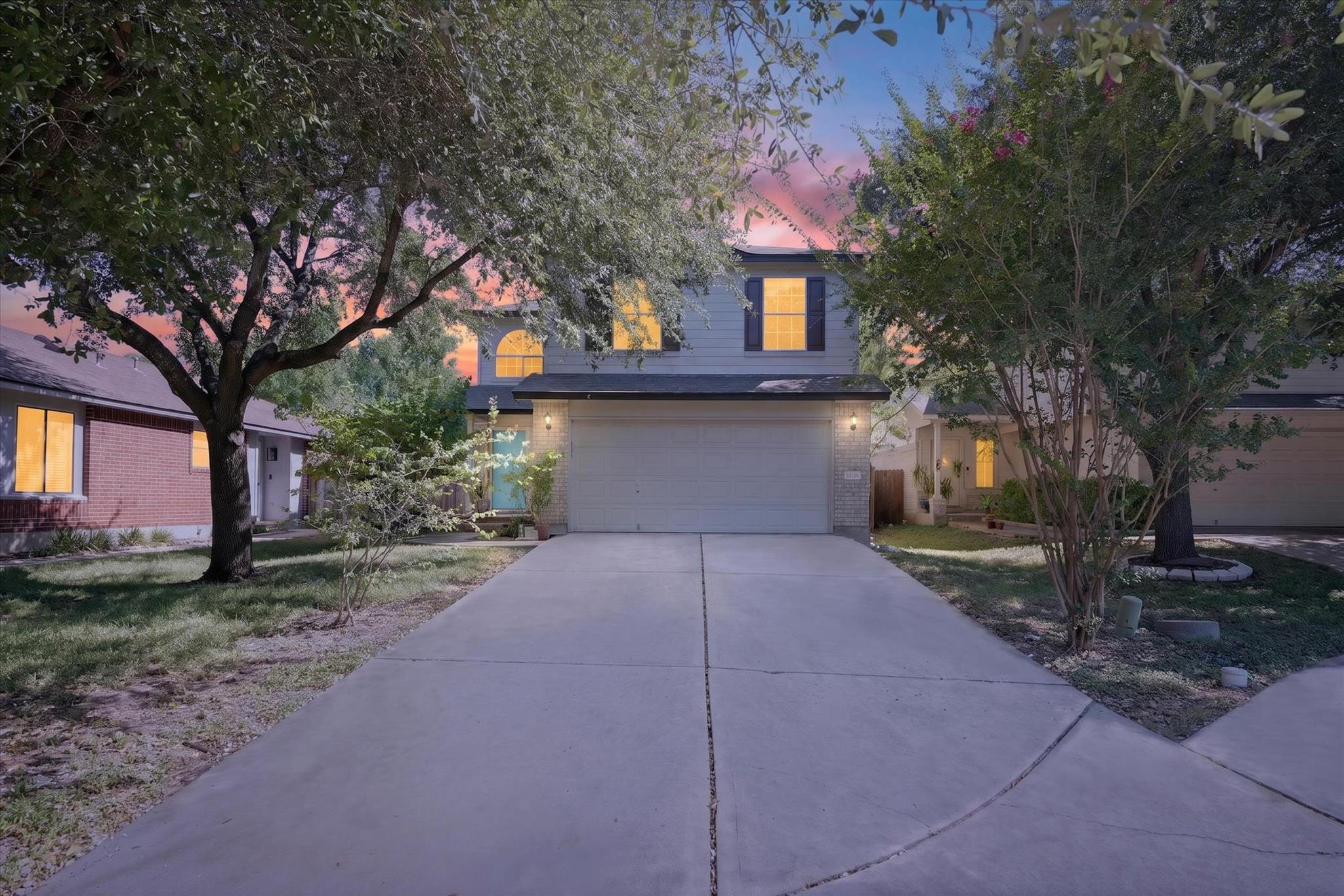 Mature trees frame the concrete driveway leading 