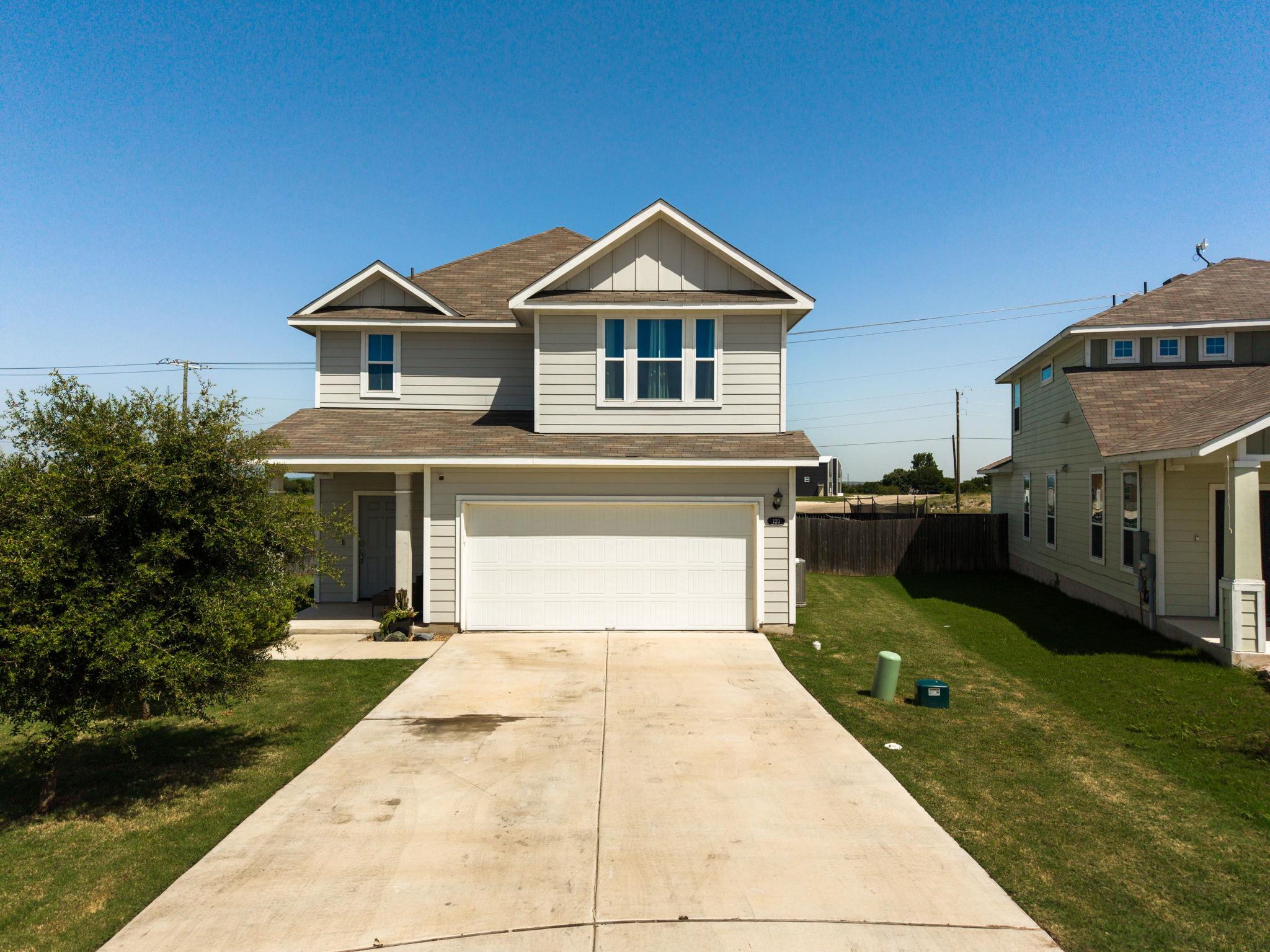 A spacious concrete driveway leads toward the int