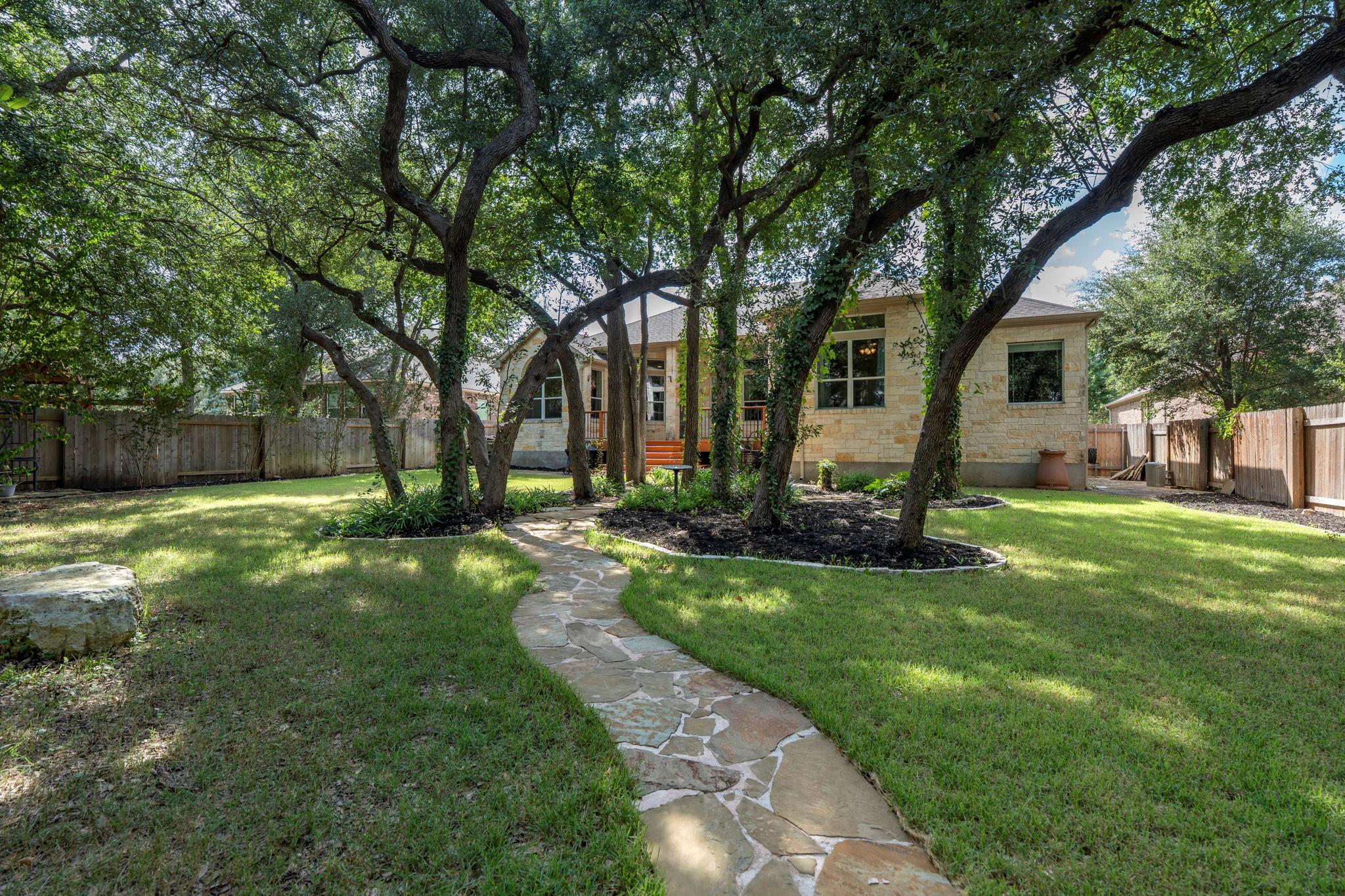 A winding stone path leads through a lush, tree-s