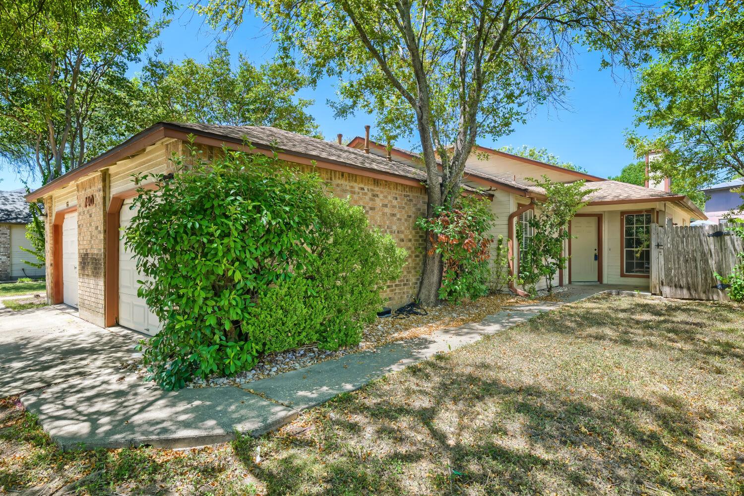 Mature trees shade the front entrance and attache