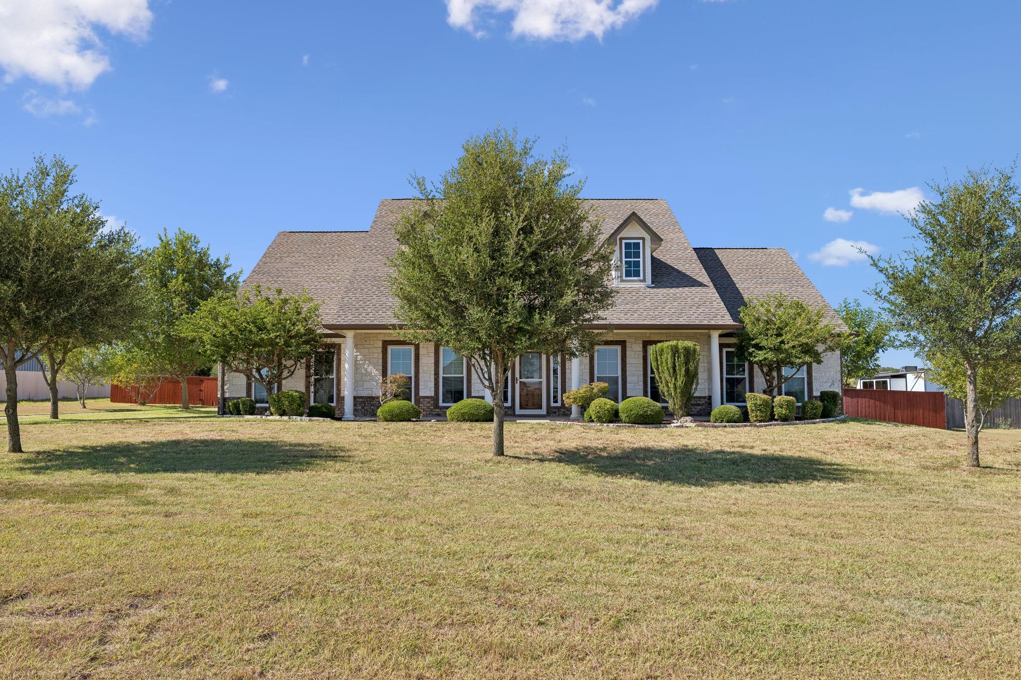 Established trees shade the expansive lawn fronti