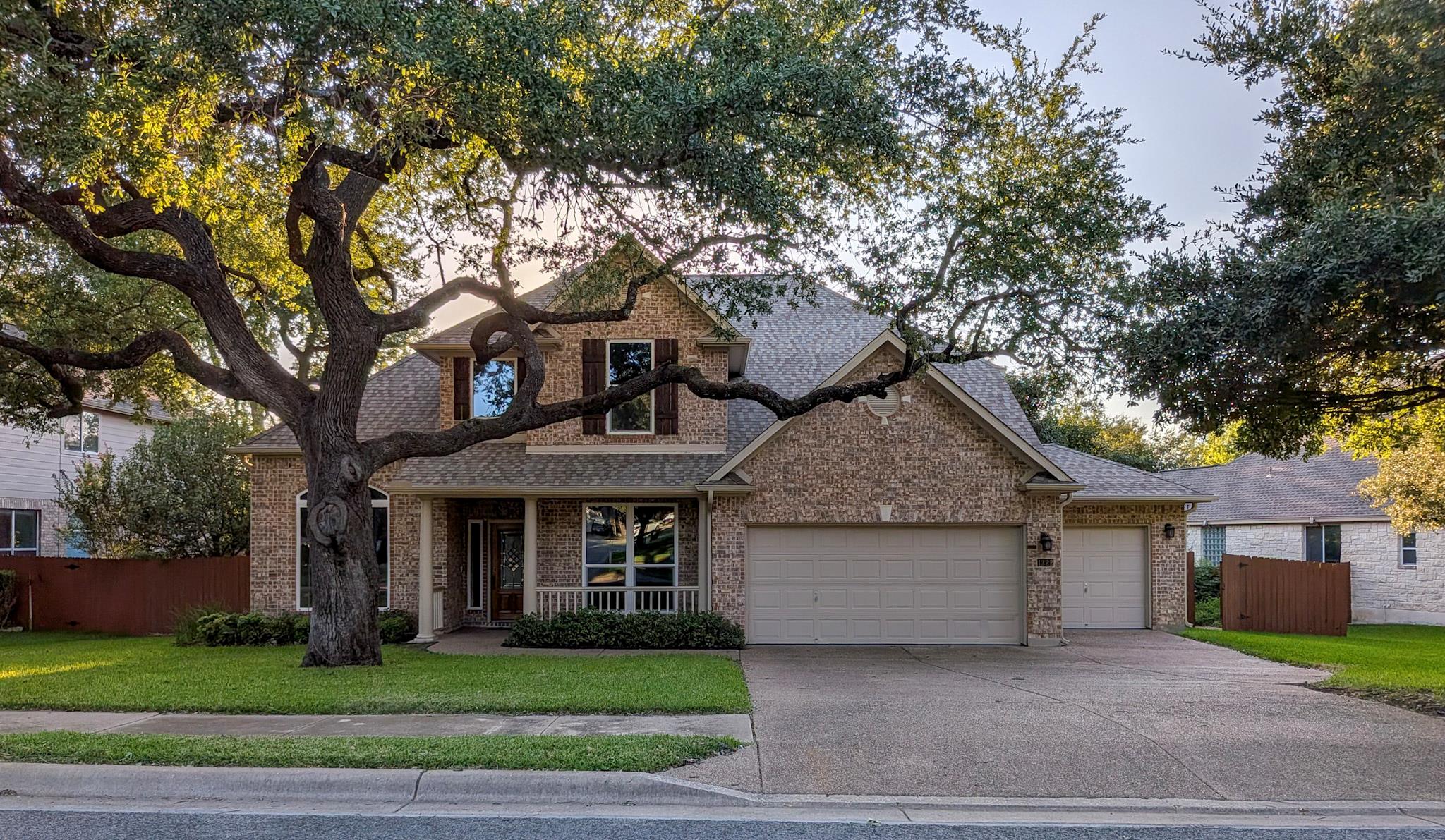 Mature shade trees frame this classic brick facad