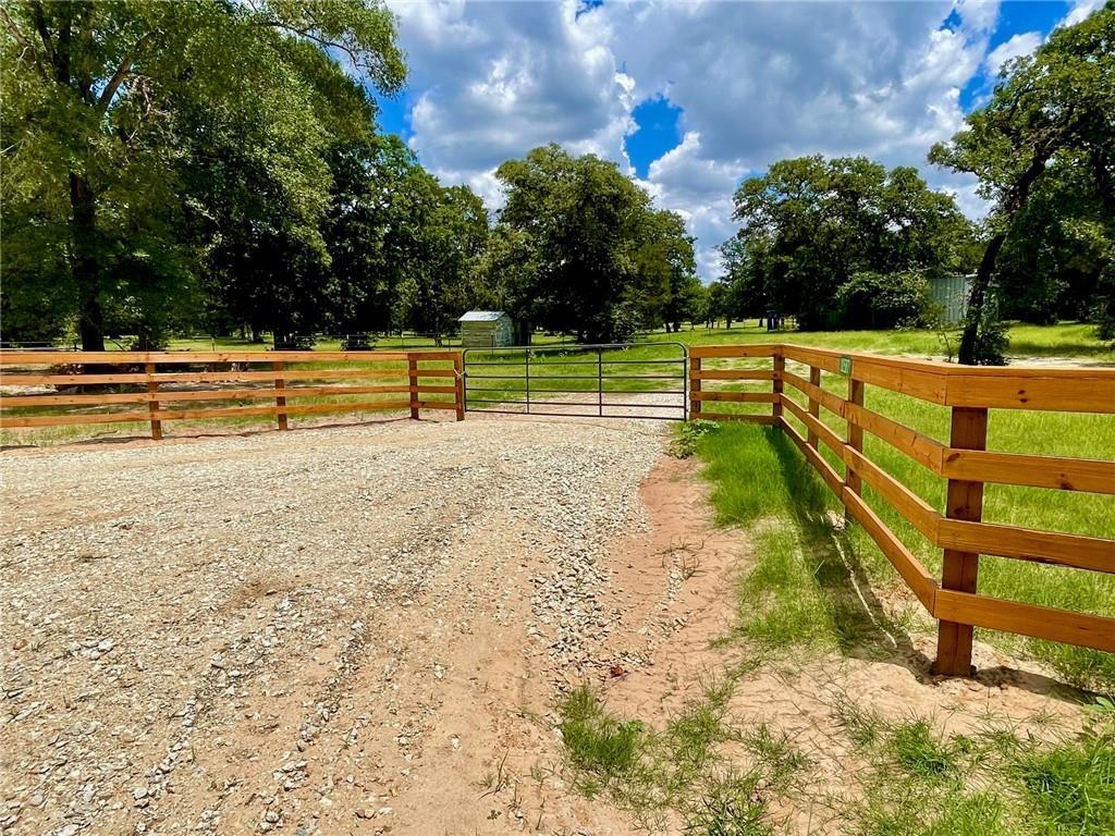 Mature trees frame a rustic wooden fence line bor