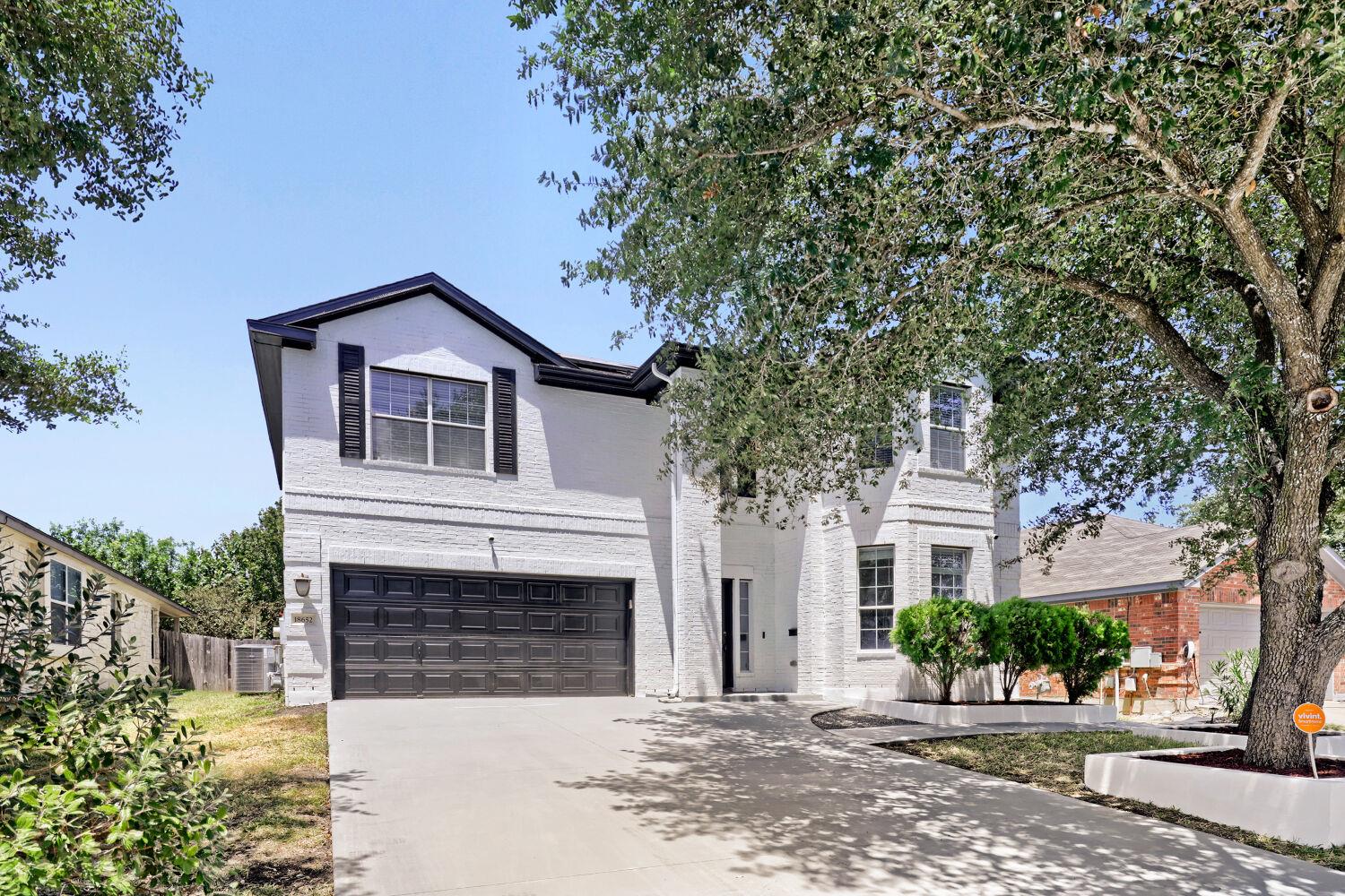 Mature trees shade a wide concrete driveway leadi