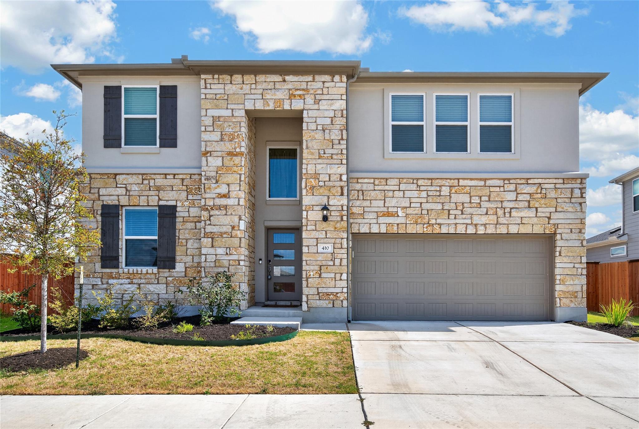 Natural stone accents and a wide concrete drivewa