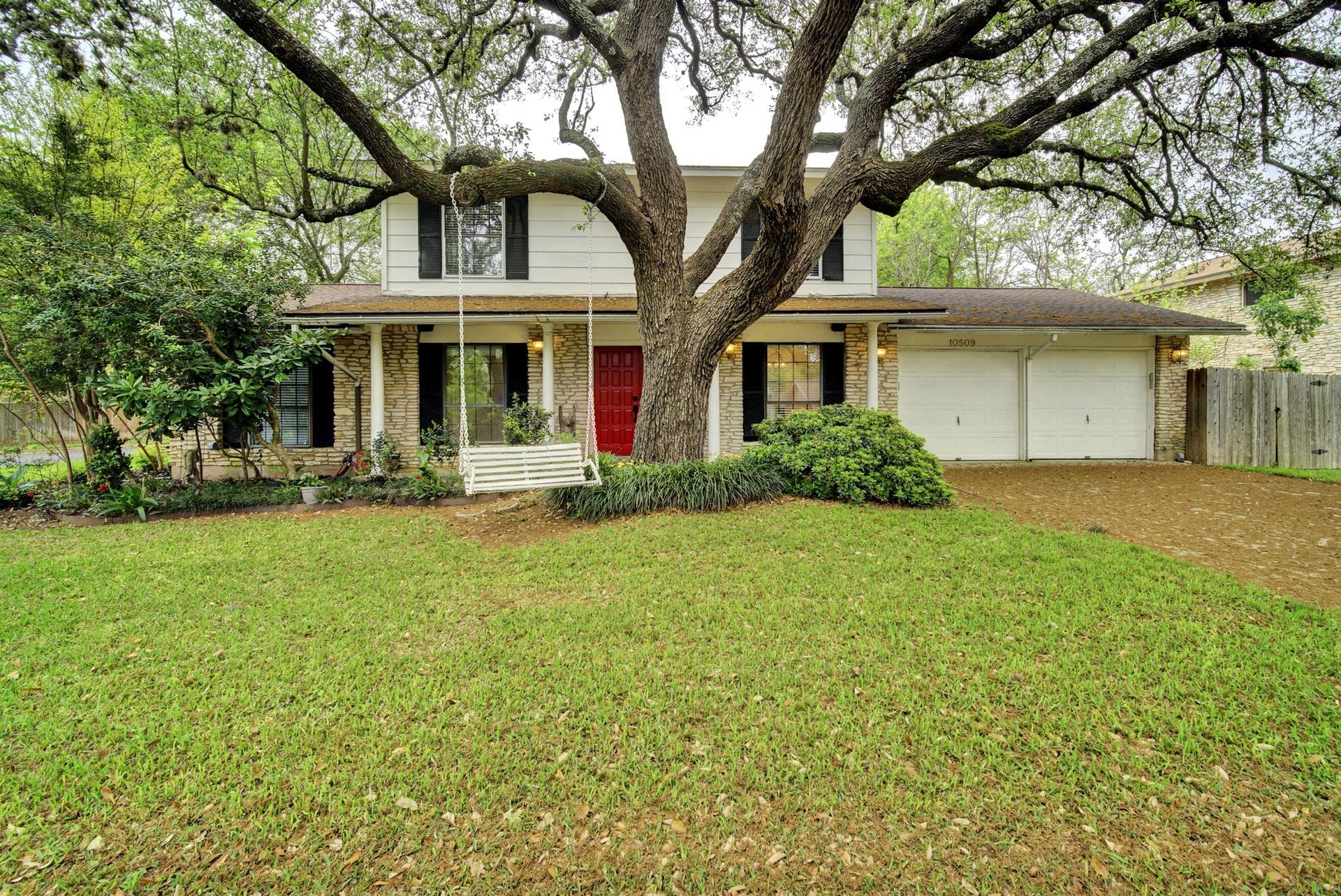 Mature oak trees shade the stone and siding exter