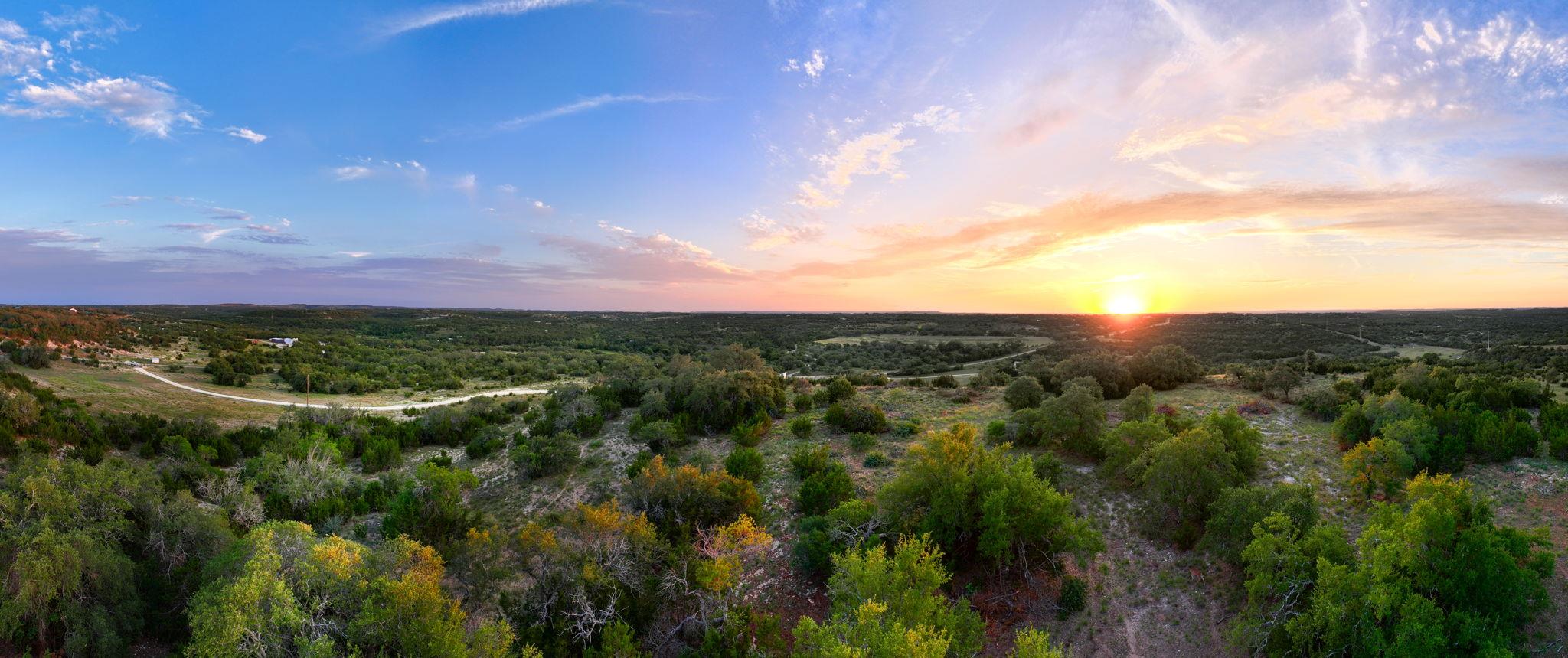 Sunset paints the sky over rolling hills and dens