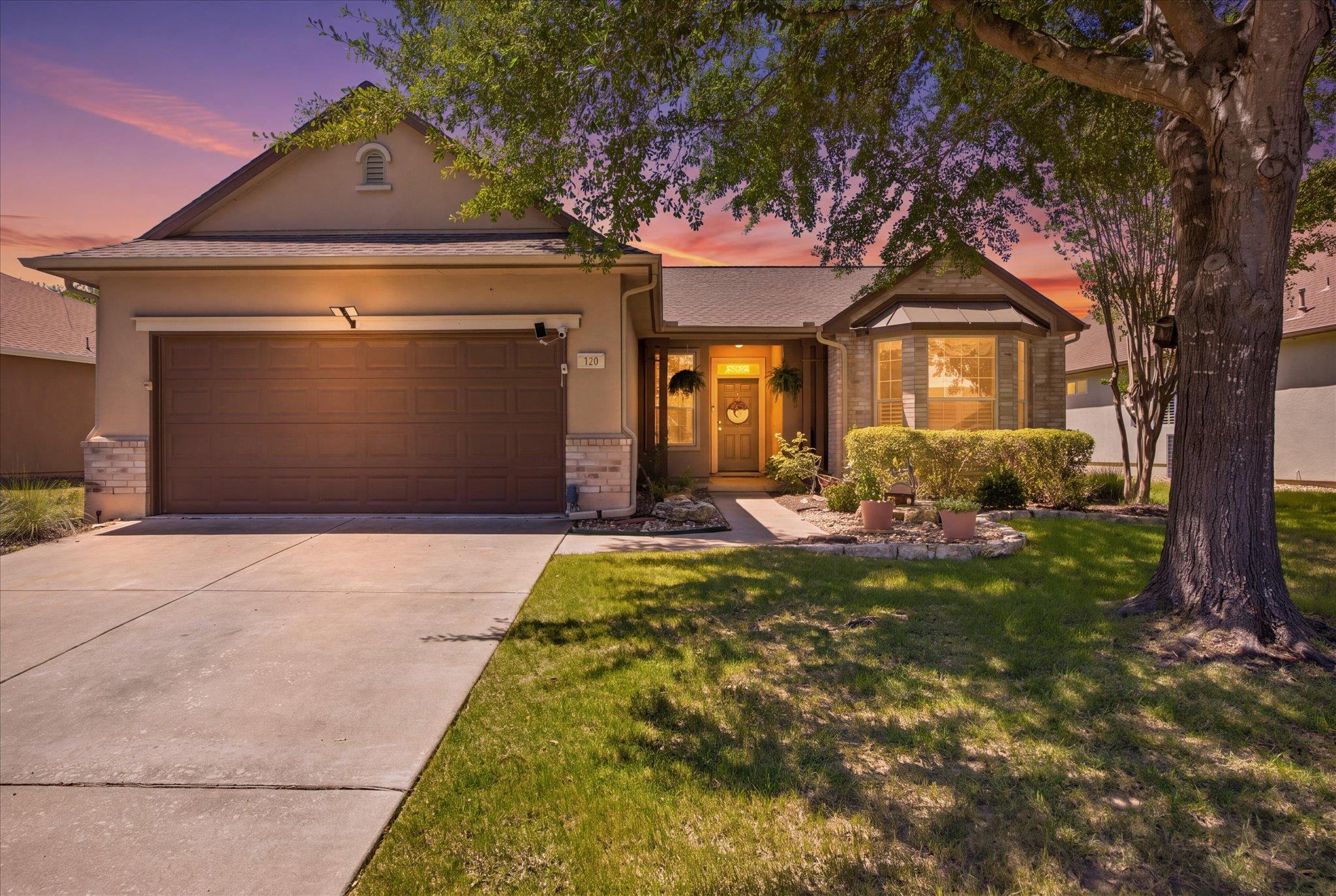 Mature trees shade the manicured front lawn leadi