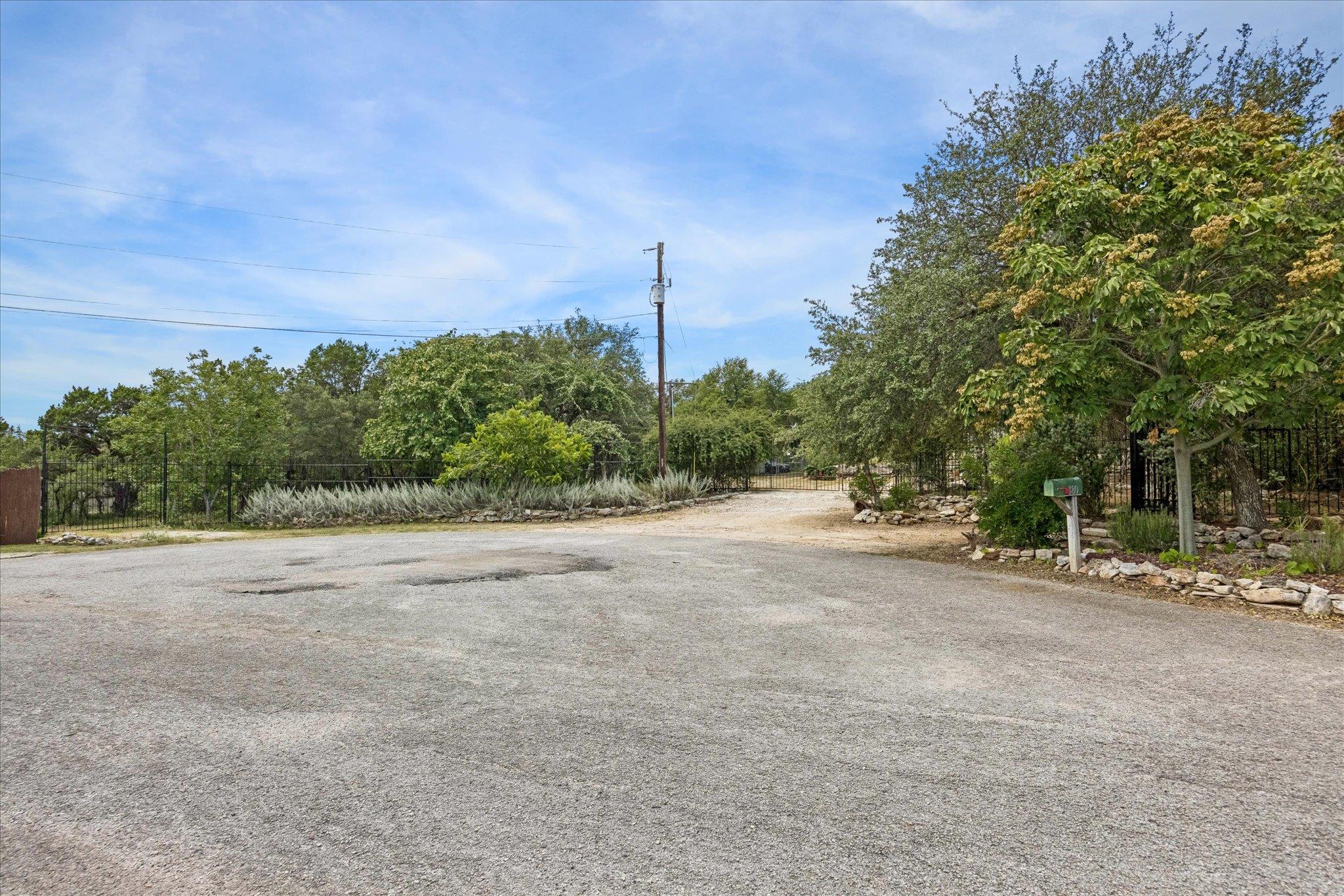 Mature trees frame a wide gravel driveway leading