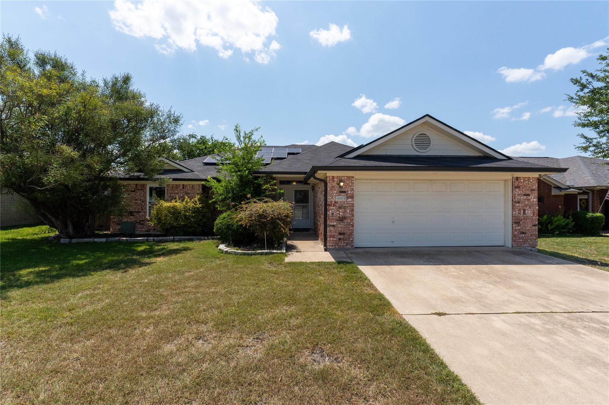 Brick accents and a classic concrete driveway fra