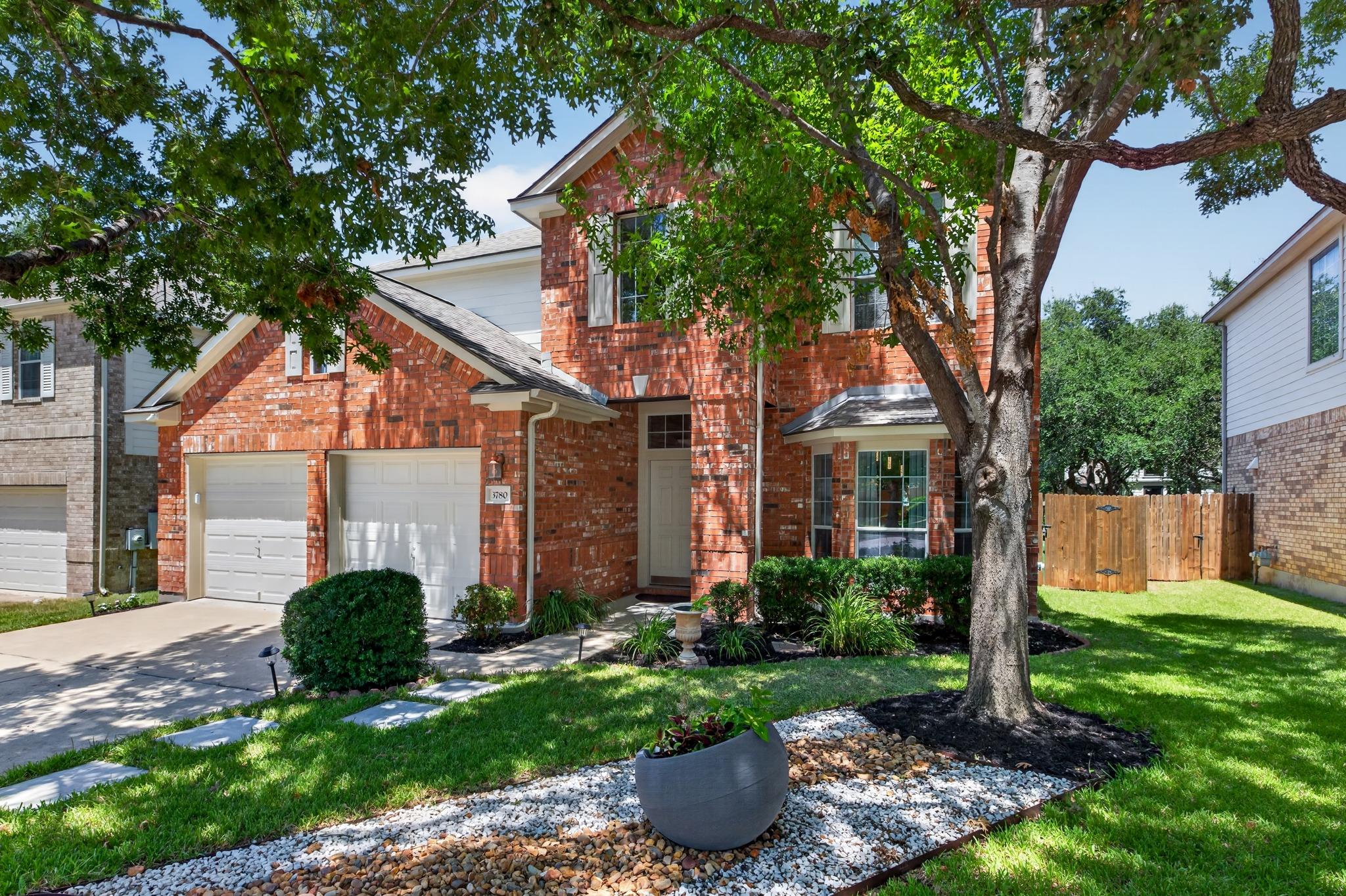 Mature trees shade the classic brick exterior and
