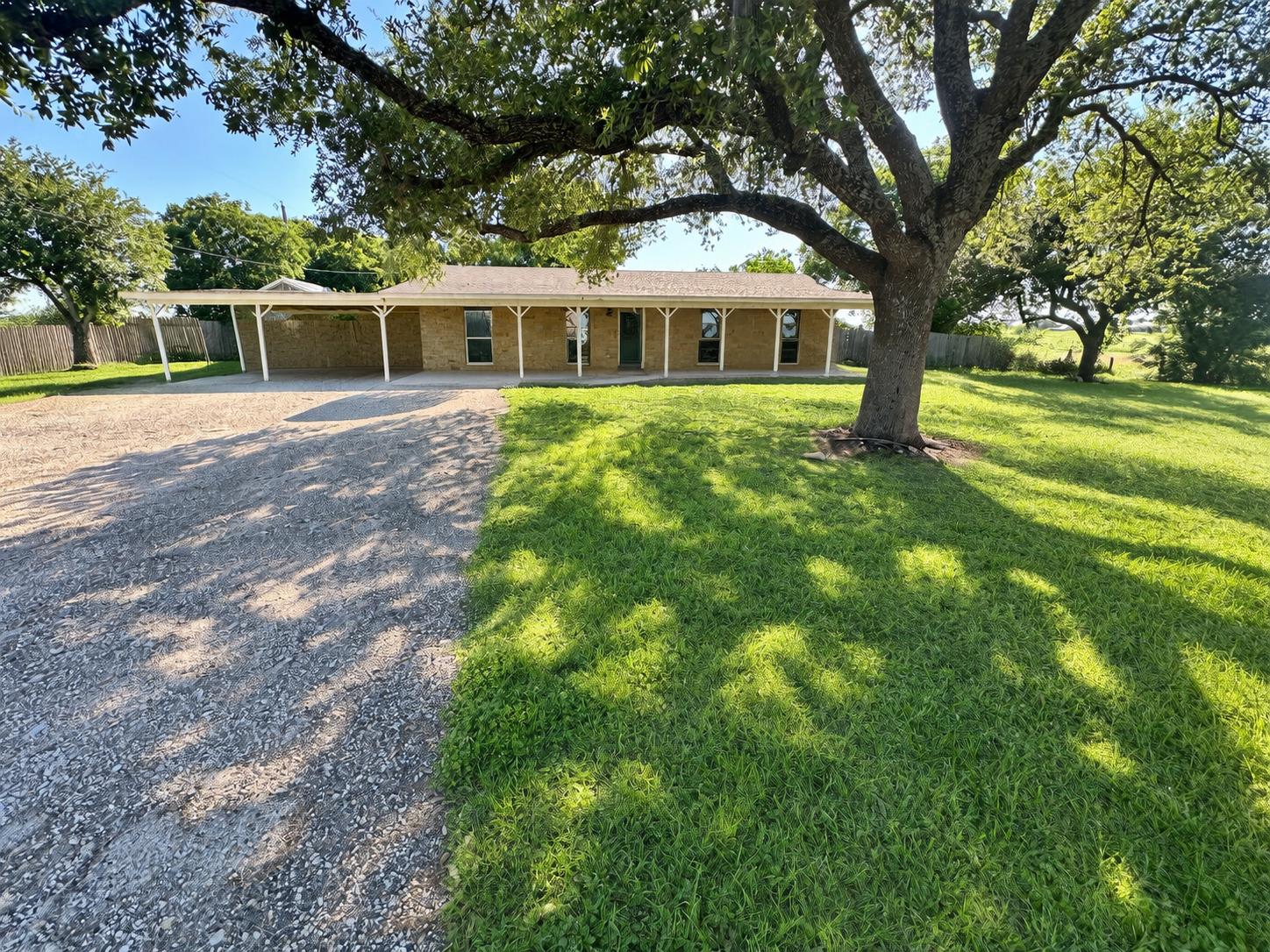 Mature shade trees frame this classic brick singl
