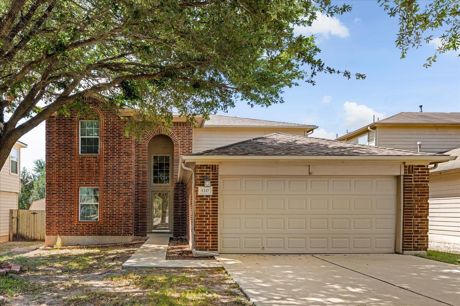 Mature trees shade a classic brick facade with an