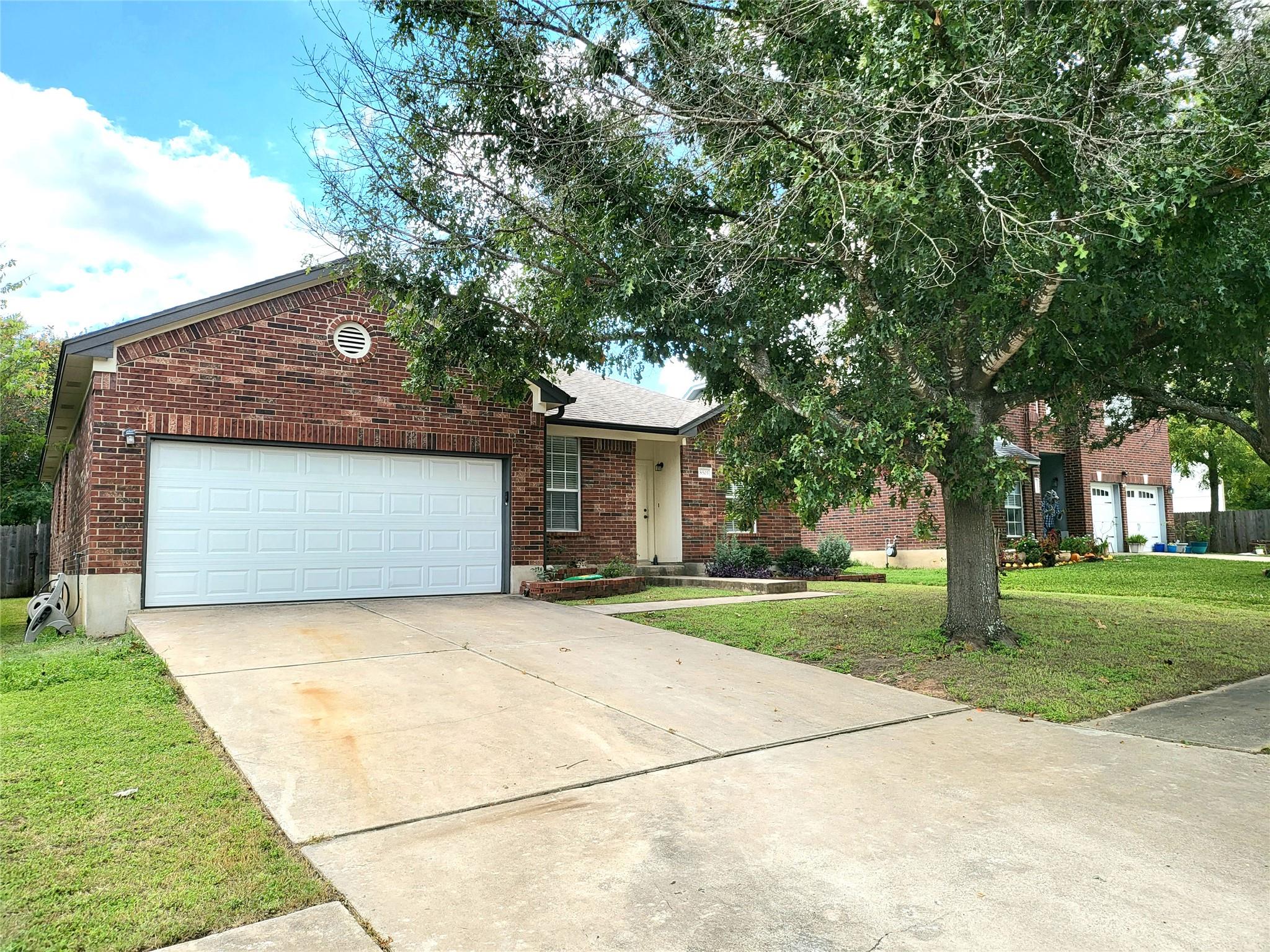 Mature trees shade a wide concrete driveway leadi
