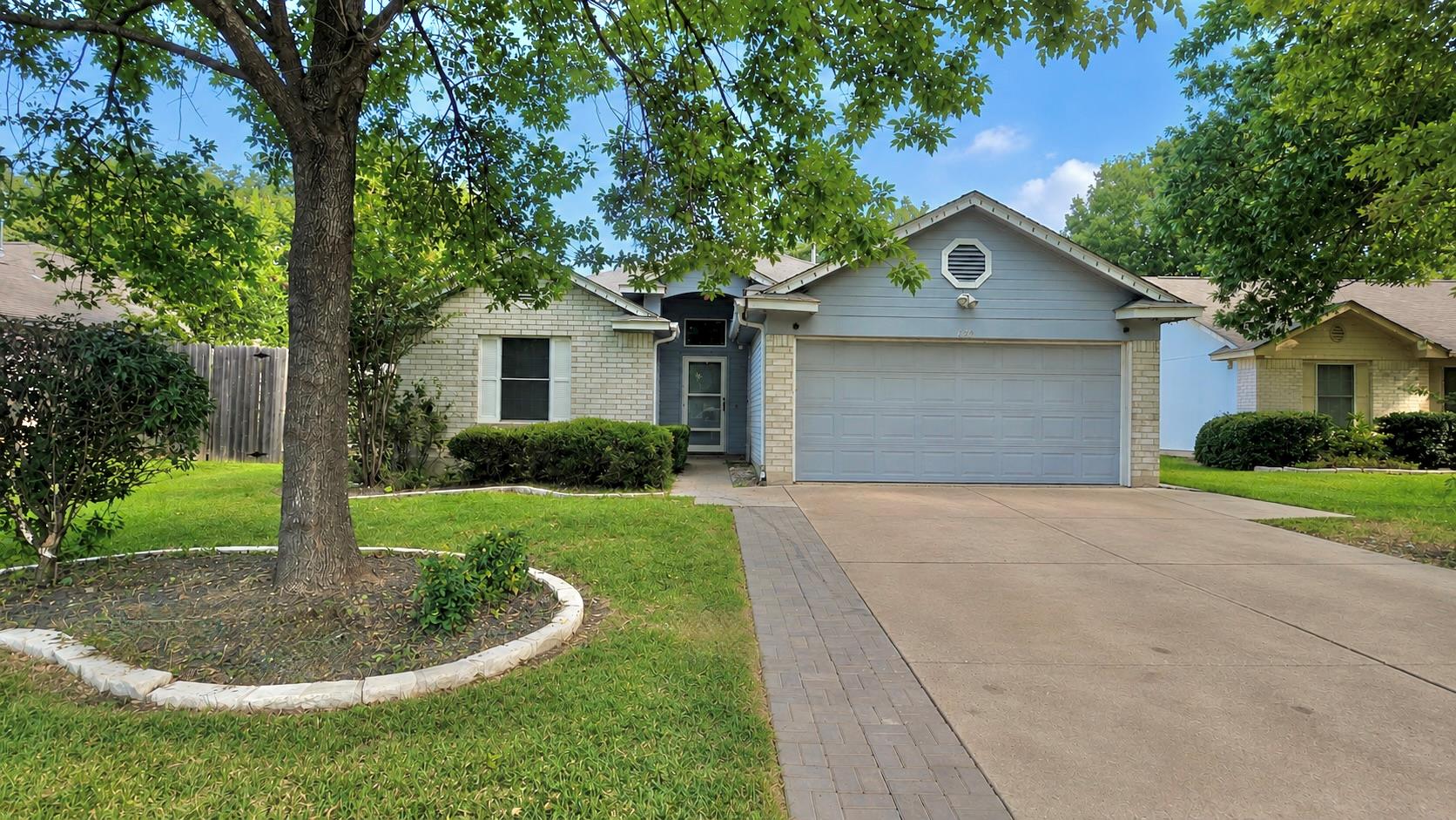 Mature trees shade the front lawn and concrete dr