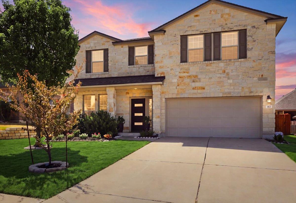 Textured stone siding and a wide concrete drivewa