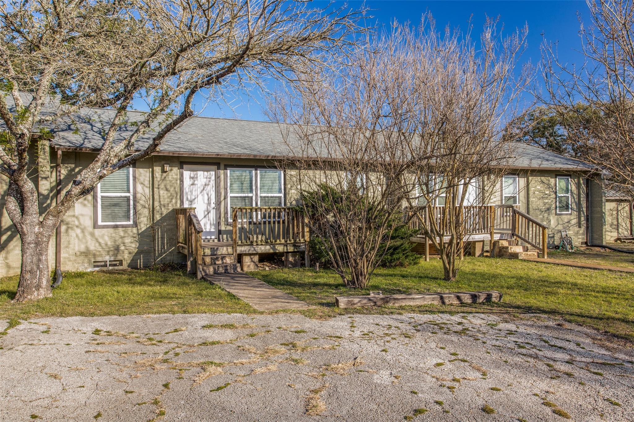 Mature trees frame the front entry and wooden por