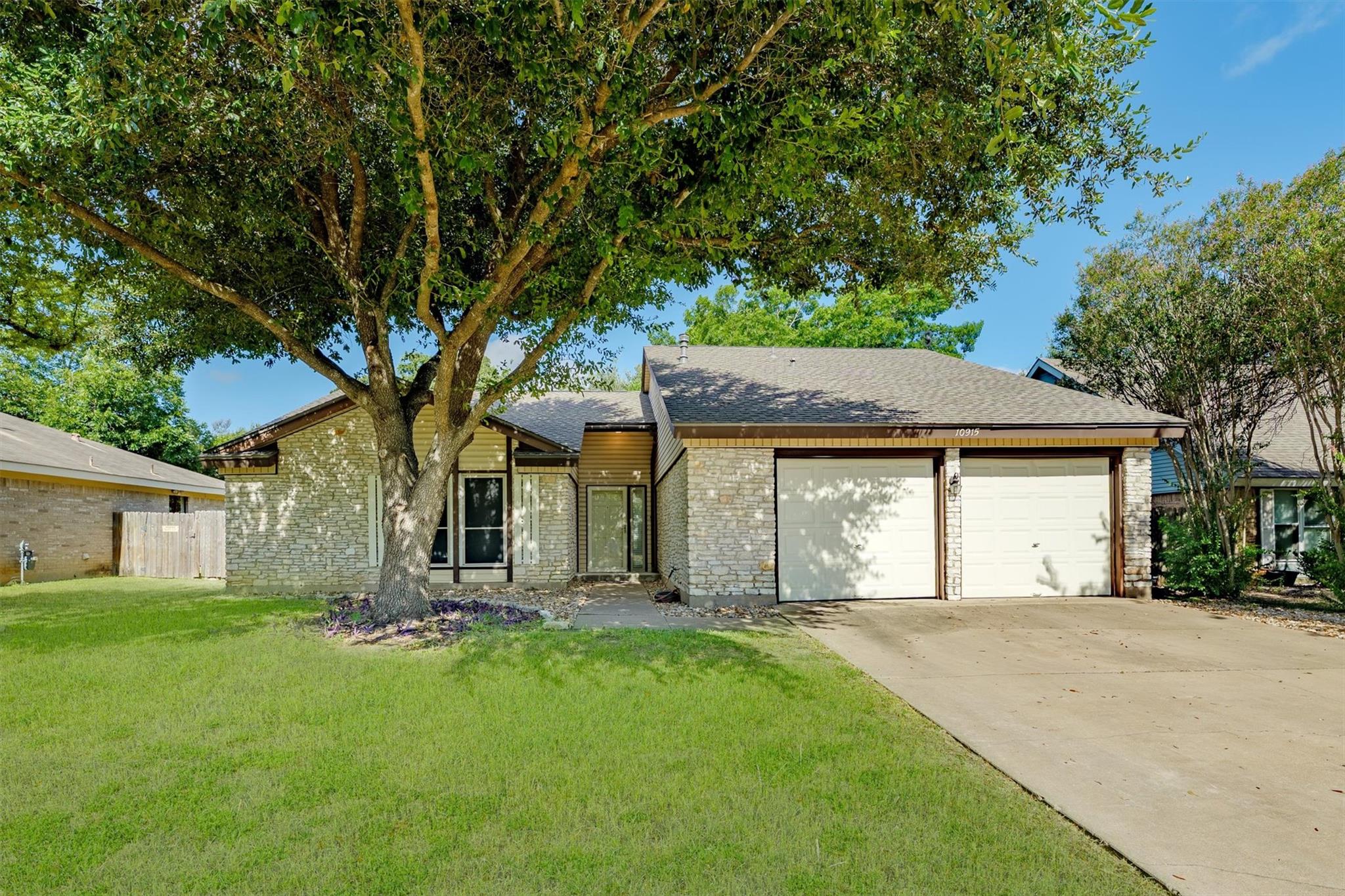 Mature trees shade the stone facade and paved dri