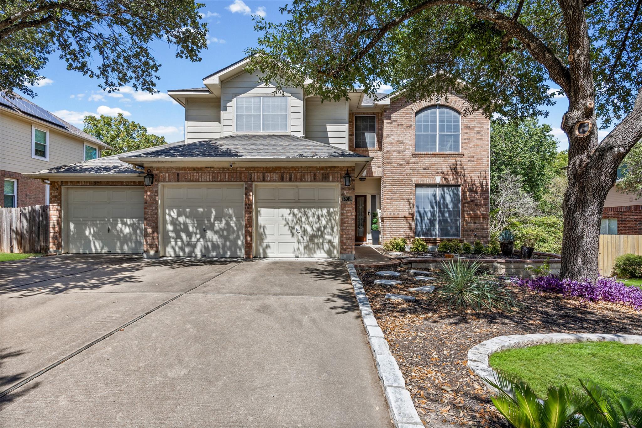 Mature trees shade a classic brick facade with a 