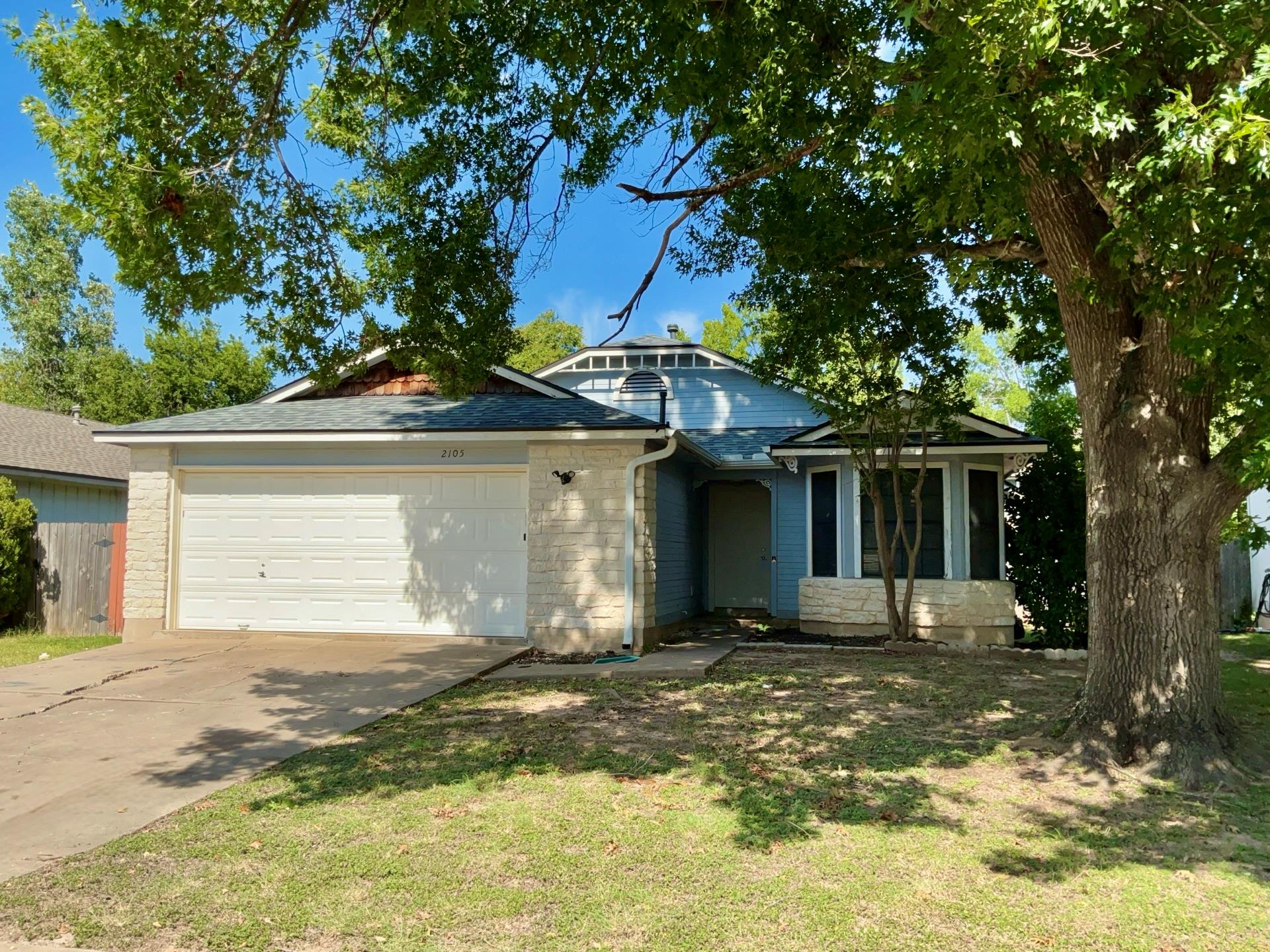 Mature trees shade a welcoming front facade compl