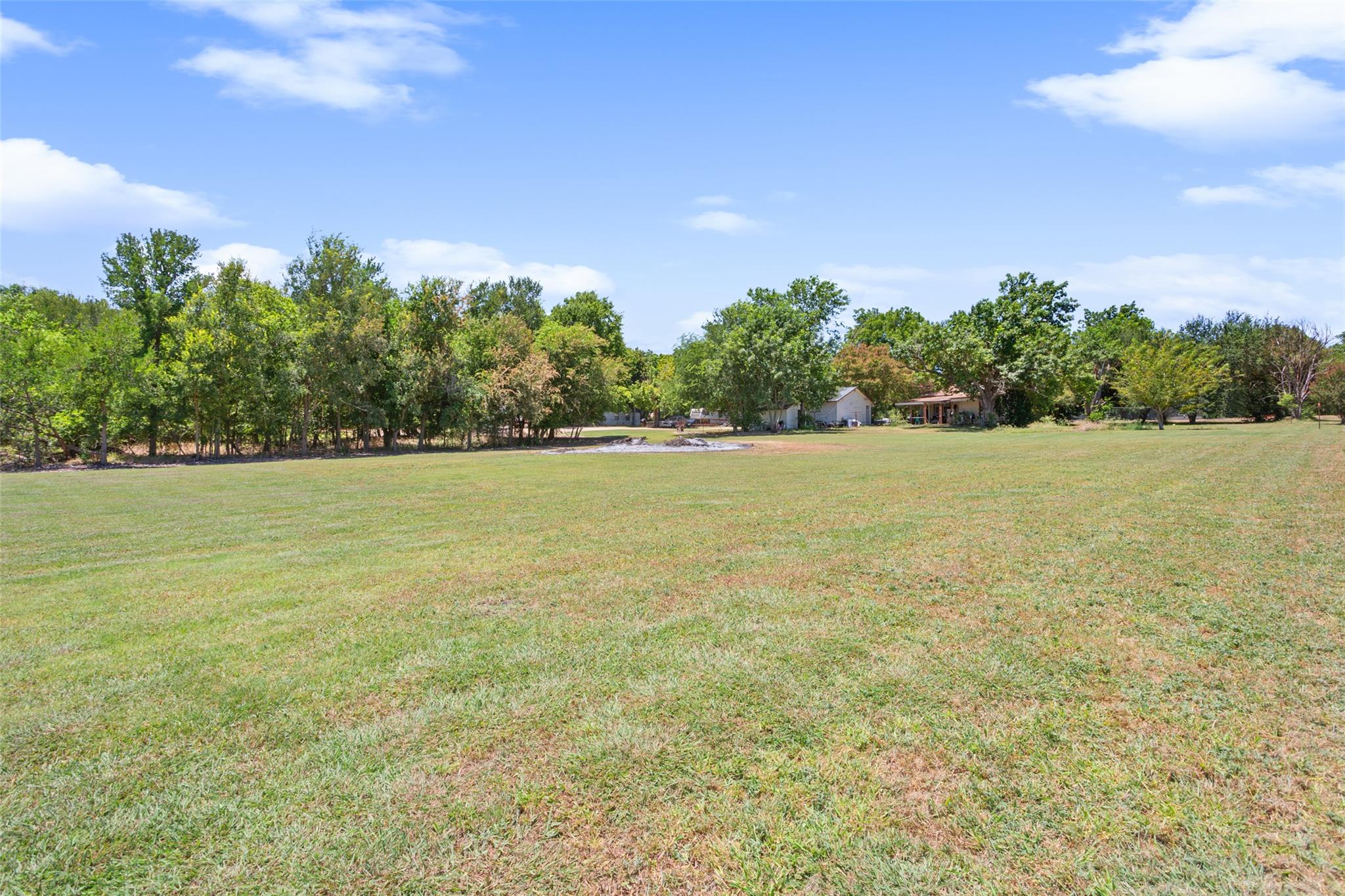 A vast grassy lawn stretches toward mature shade 