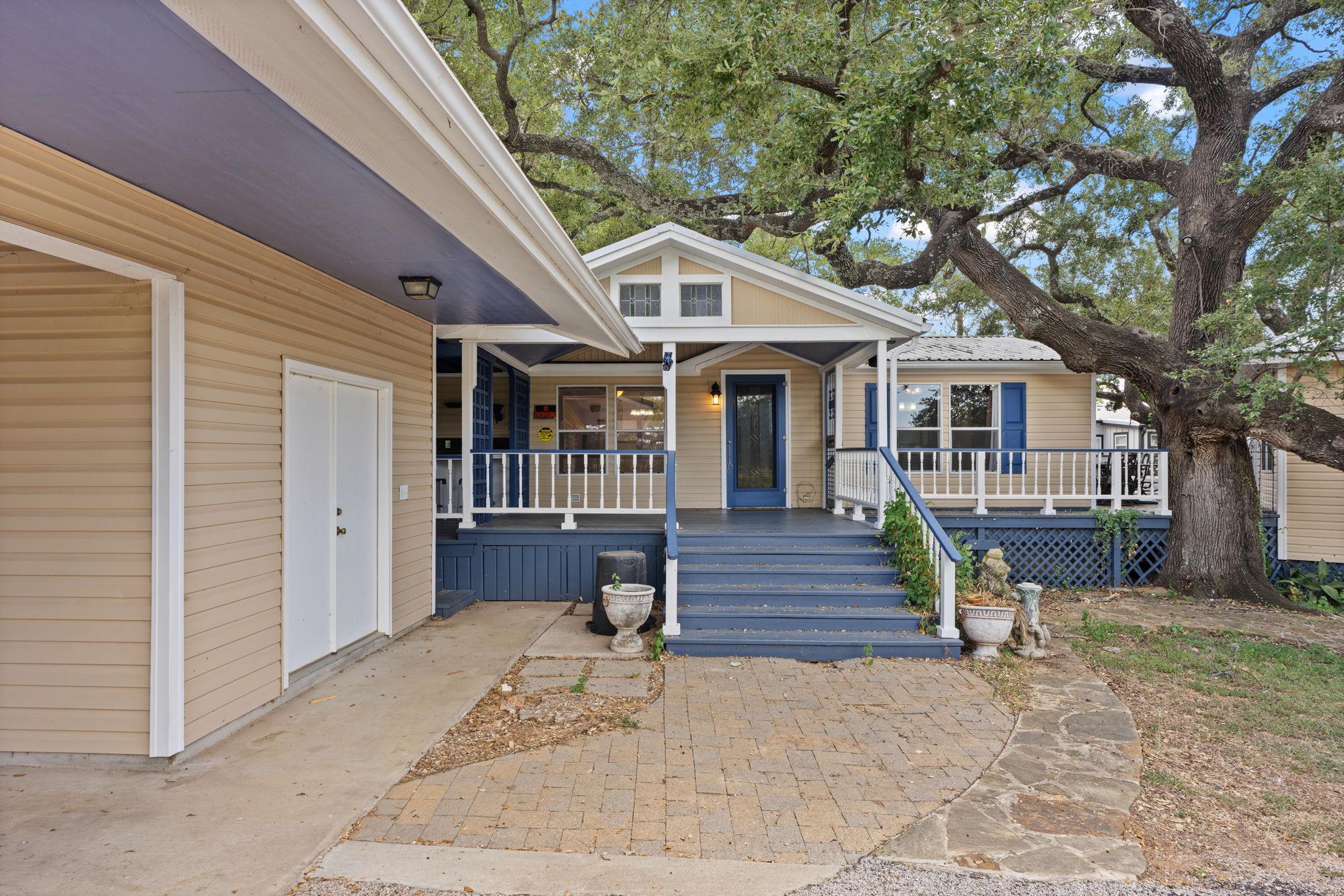 Mature shade trees frame a welcoming elevated fro