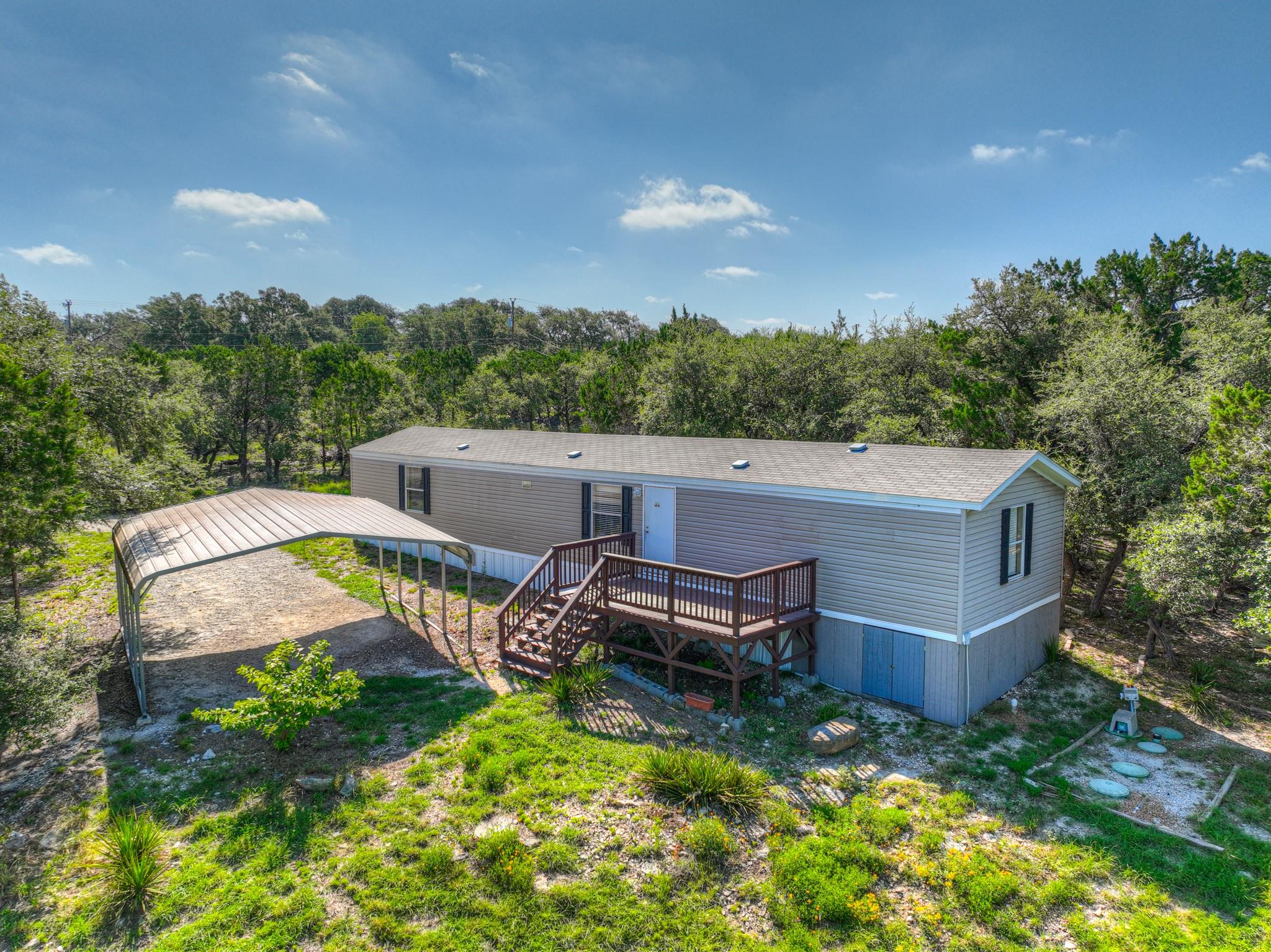 A spacious wooden deck and adjacent metal carport
