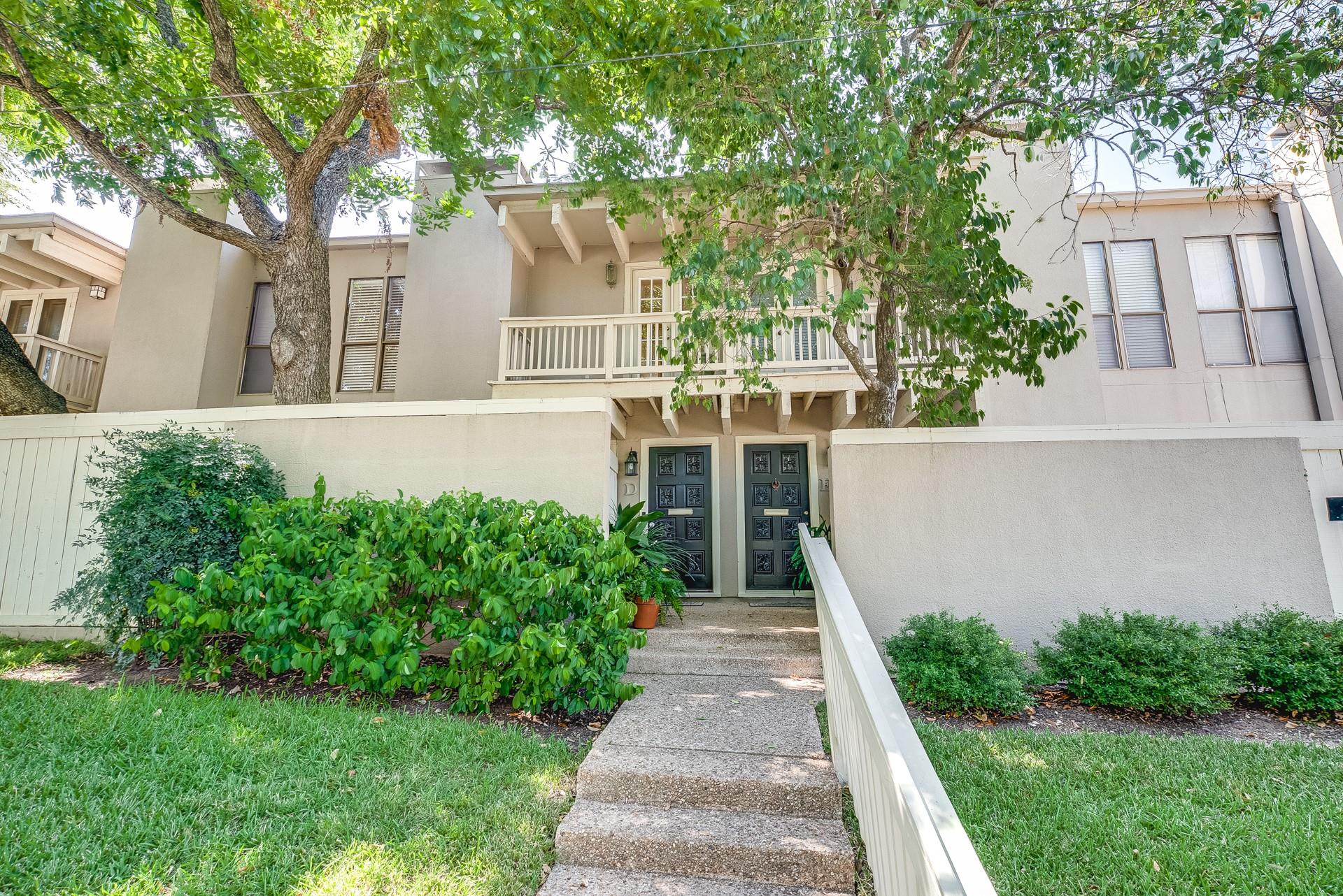 Mature trees shade a stucco townhouse entry featu