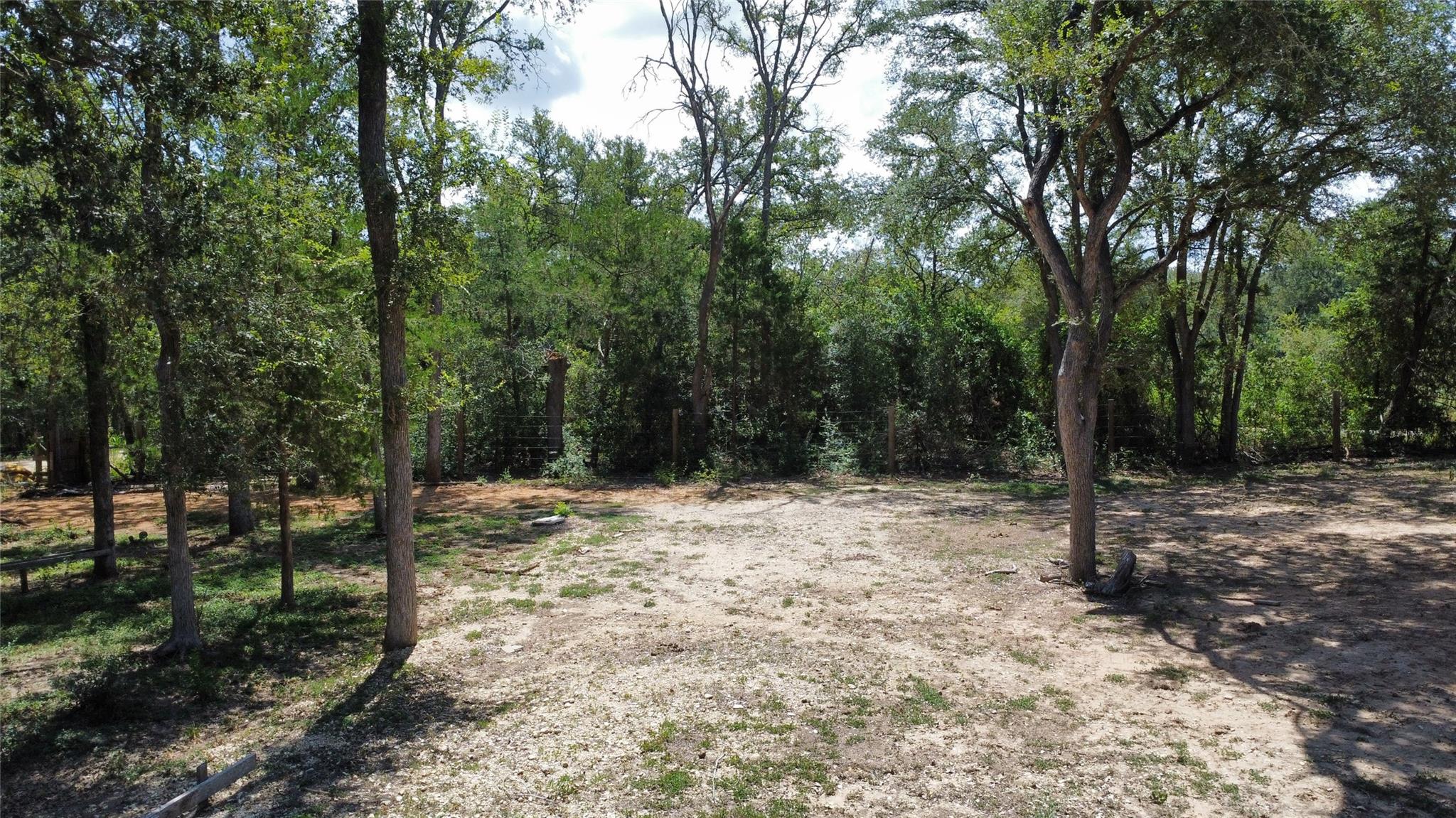 Mature trees frame a spacious, cleared building s