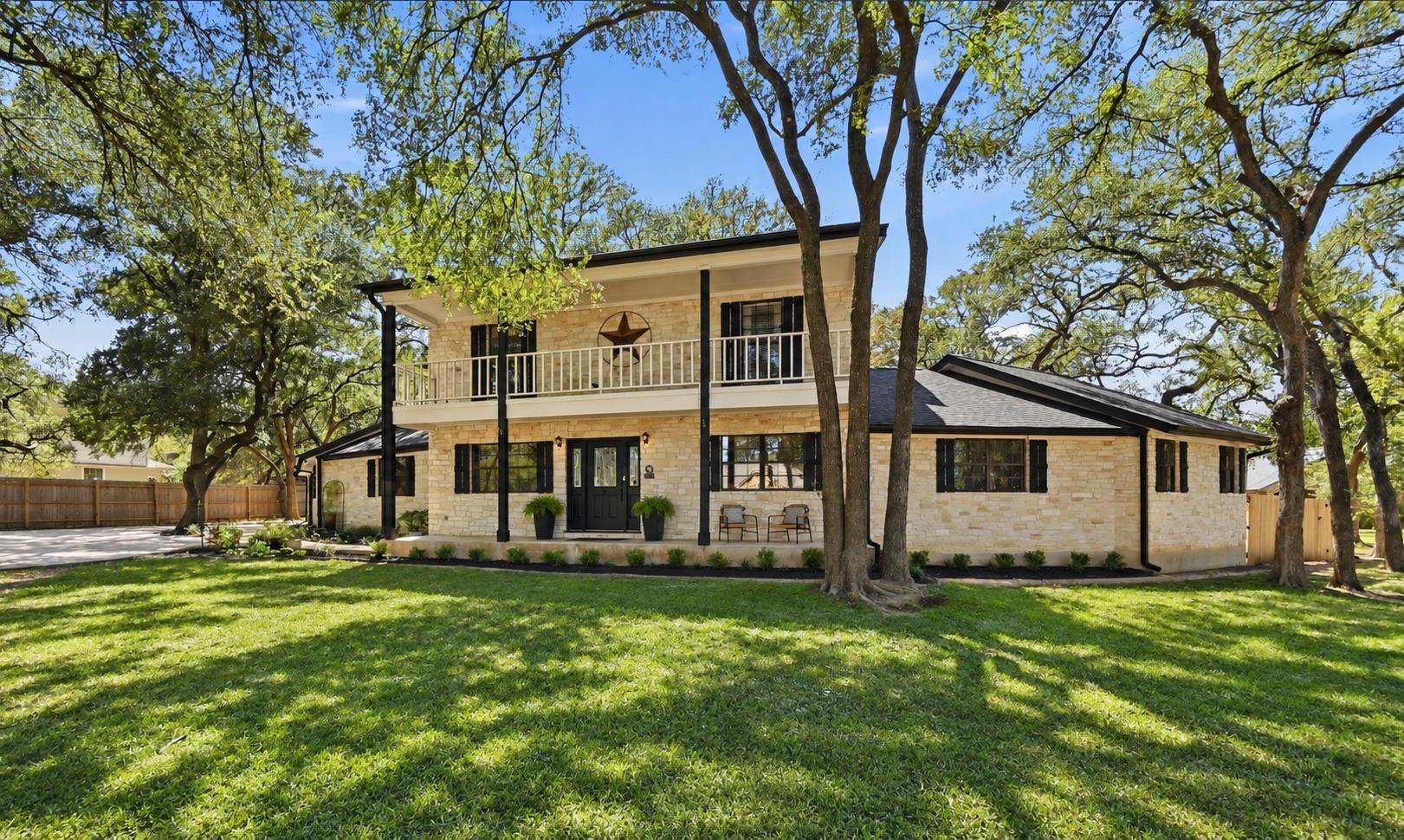 Mature trees shade a classic two-story stone faca
