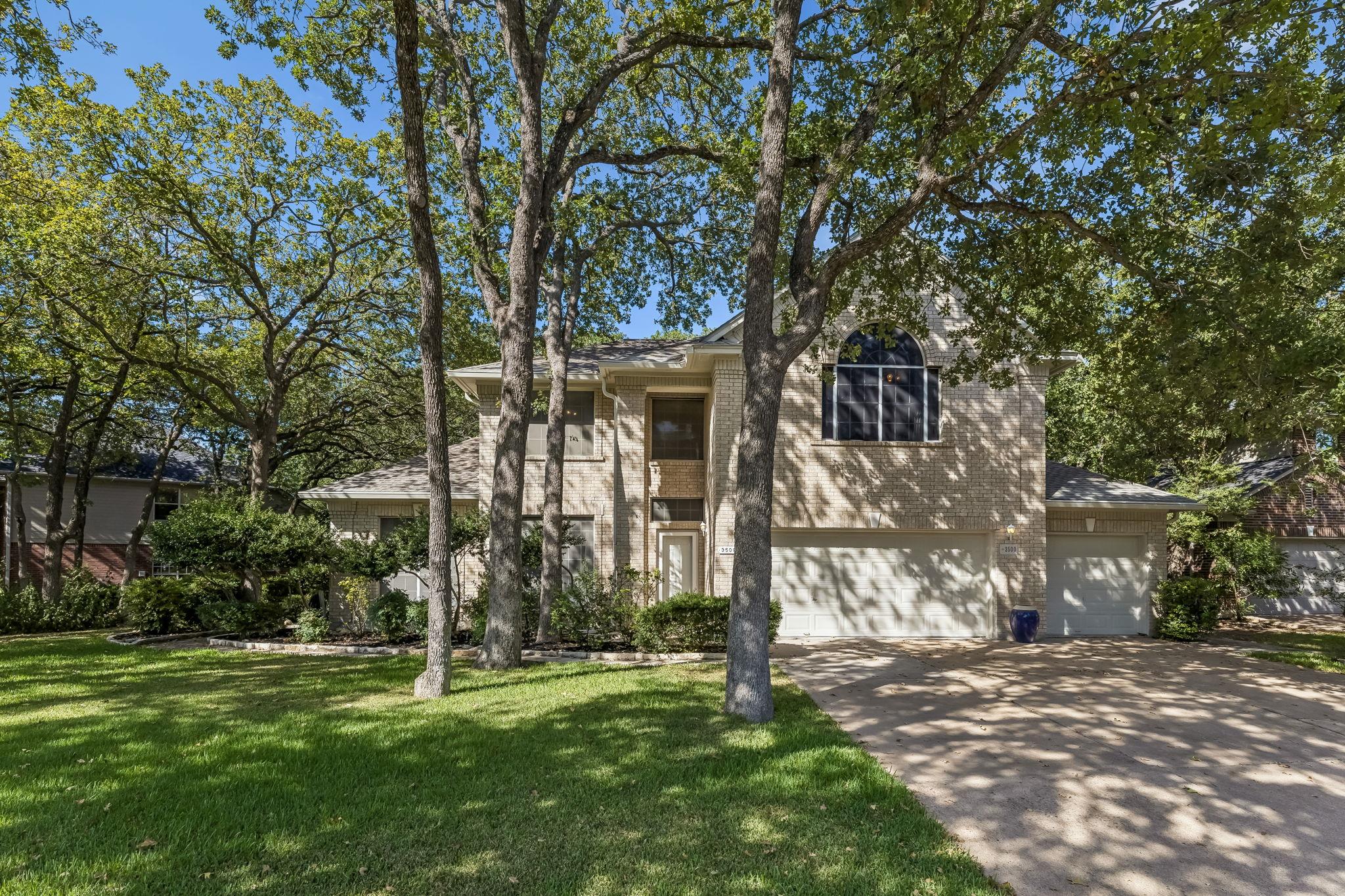 Mature trees shade a classic brick facade with an