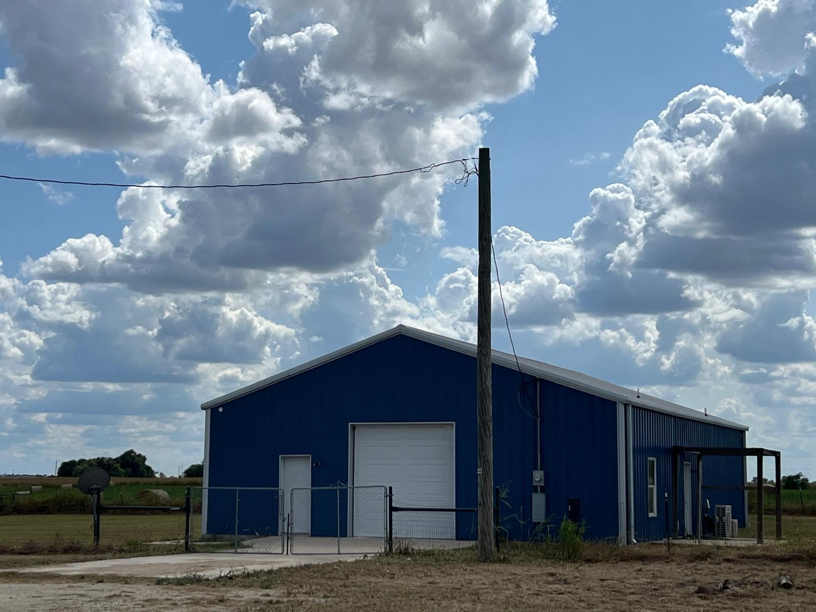 A metal outbuilding sits under a bright sky with 