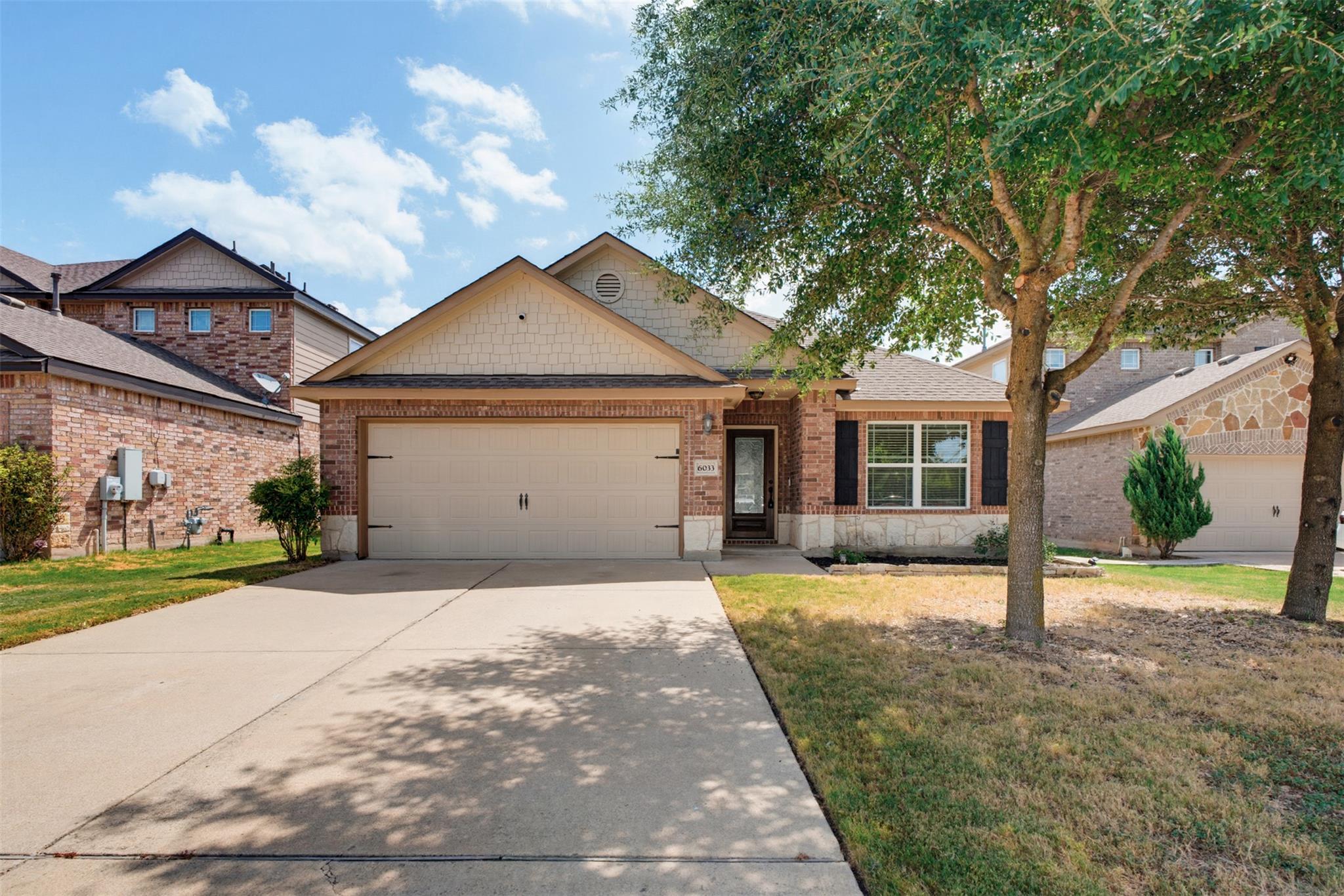 Mature trees frame a charming brick exterior with
