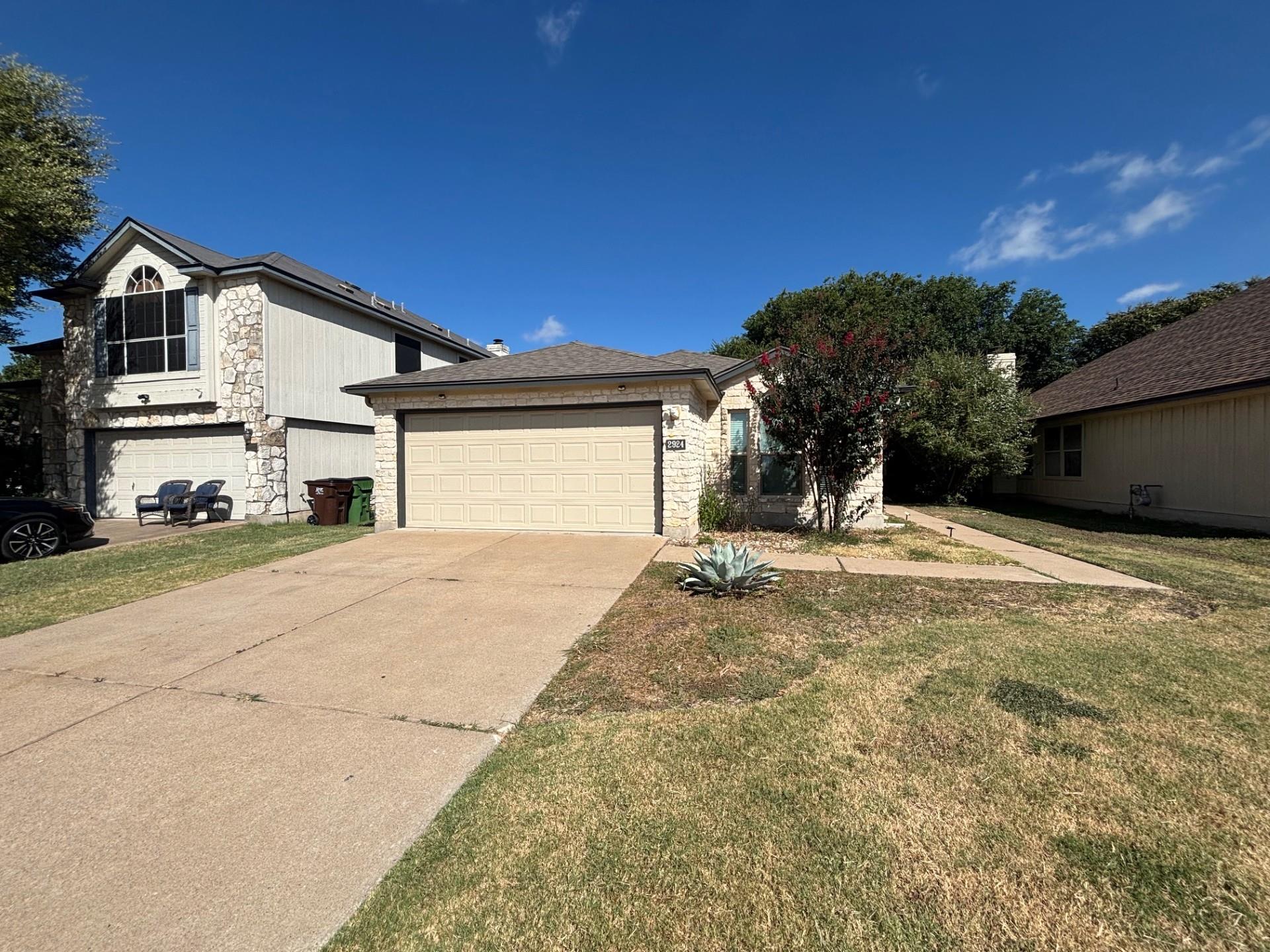Natural stone accents and a wide driveway define 
