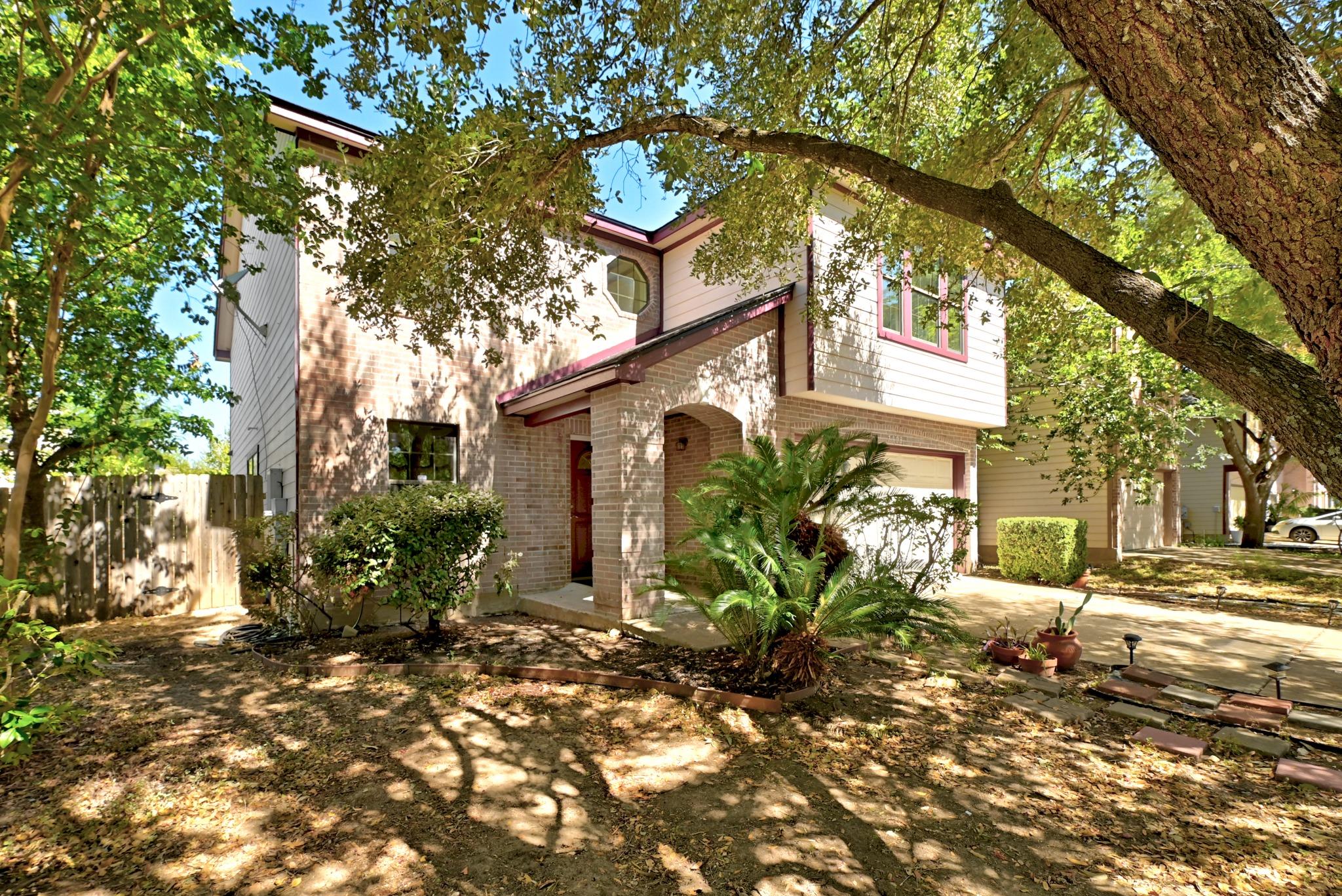 Mature trees shade a two-story home featuring bri
