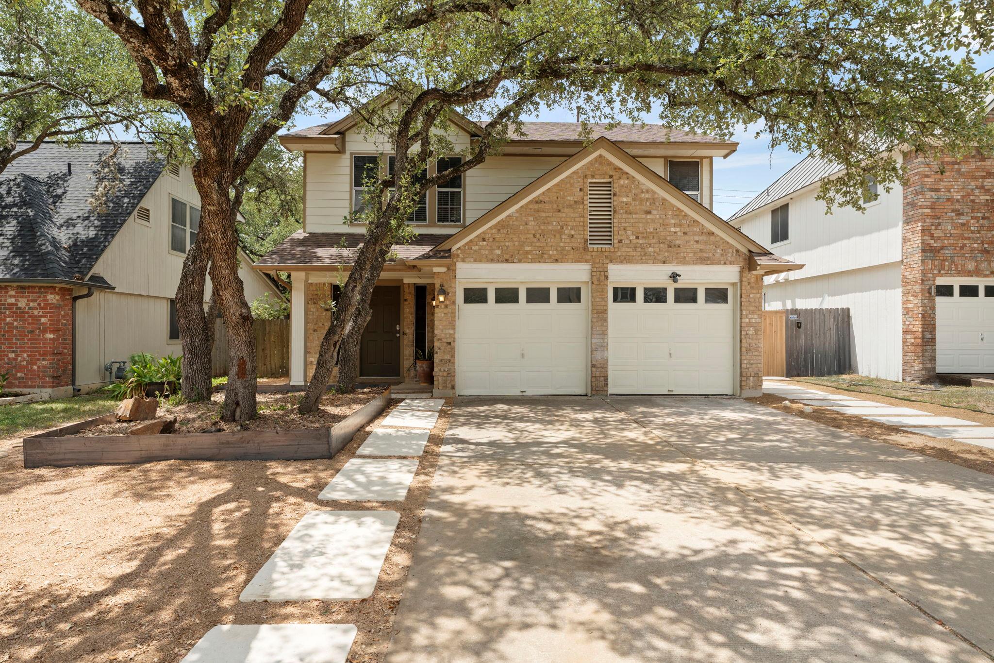 Mature shade trees frame a classic two-story faca