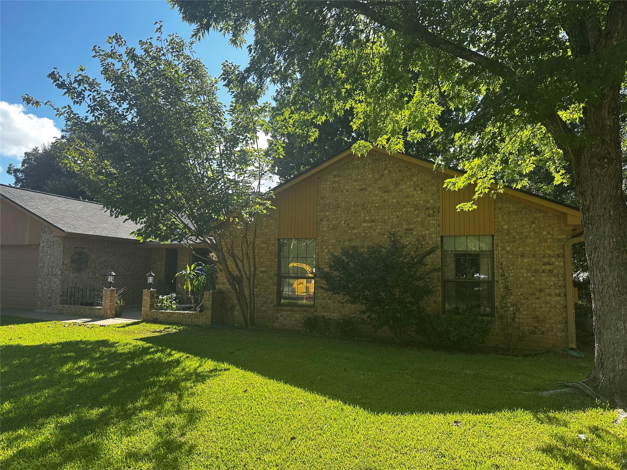 Mature trees shade a classic brick facade with la