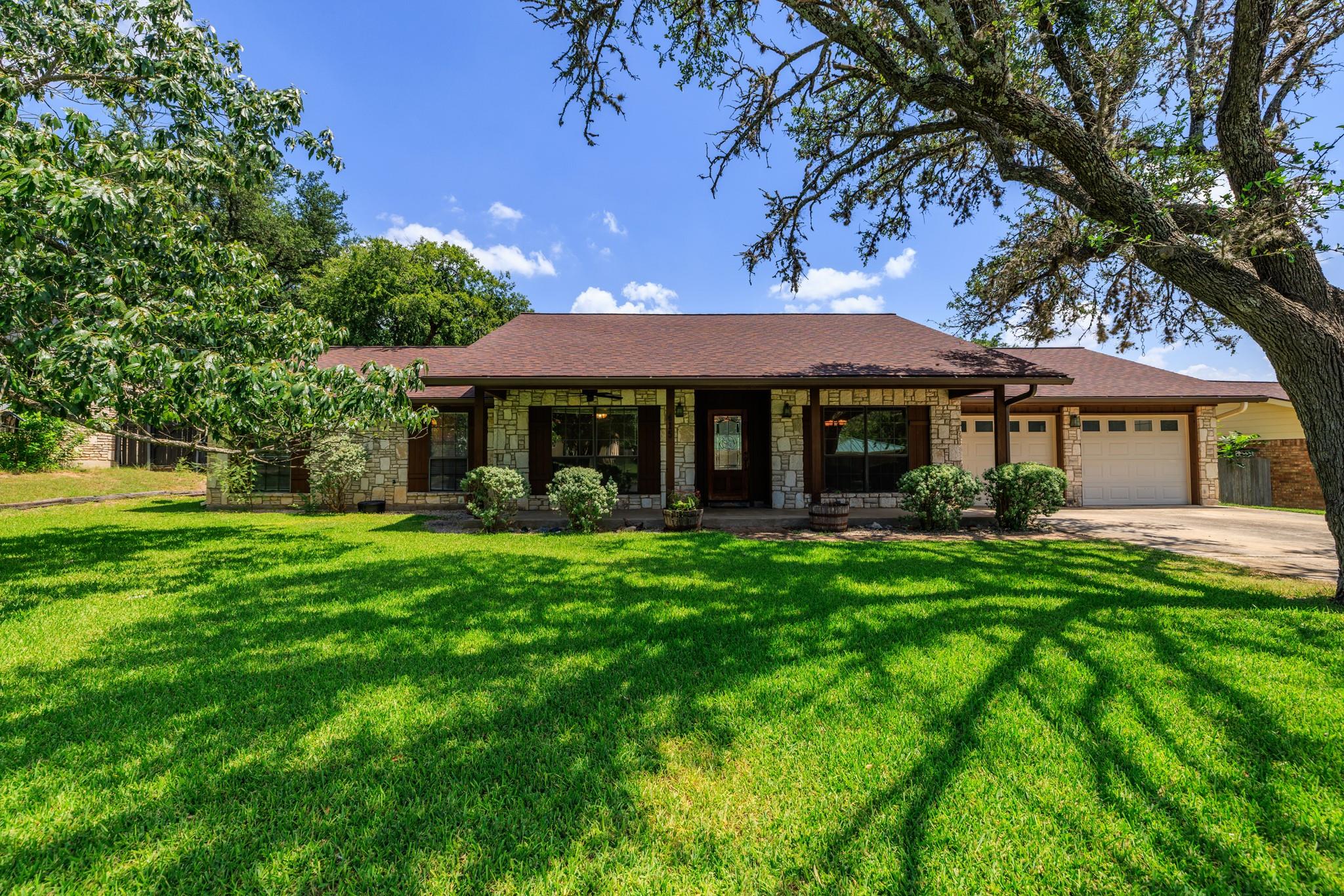 Shaded by mature trees, this stone ranch home fea